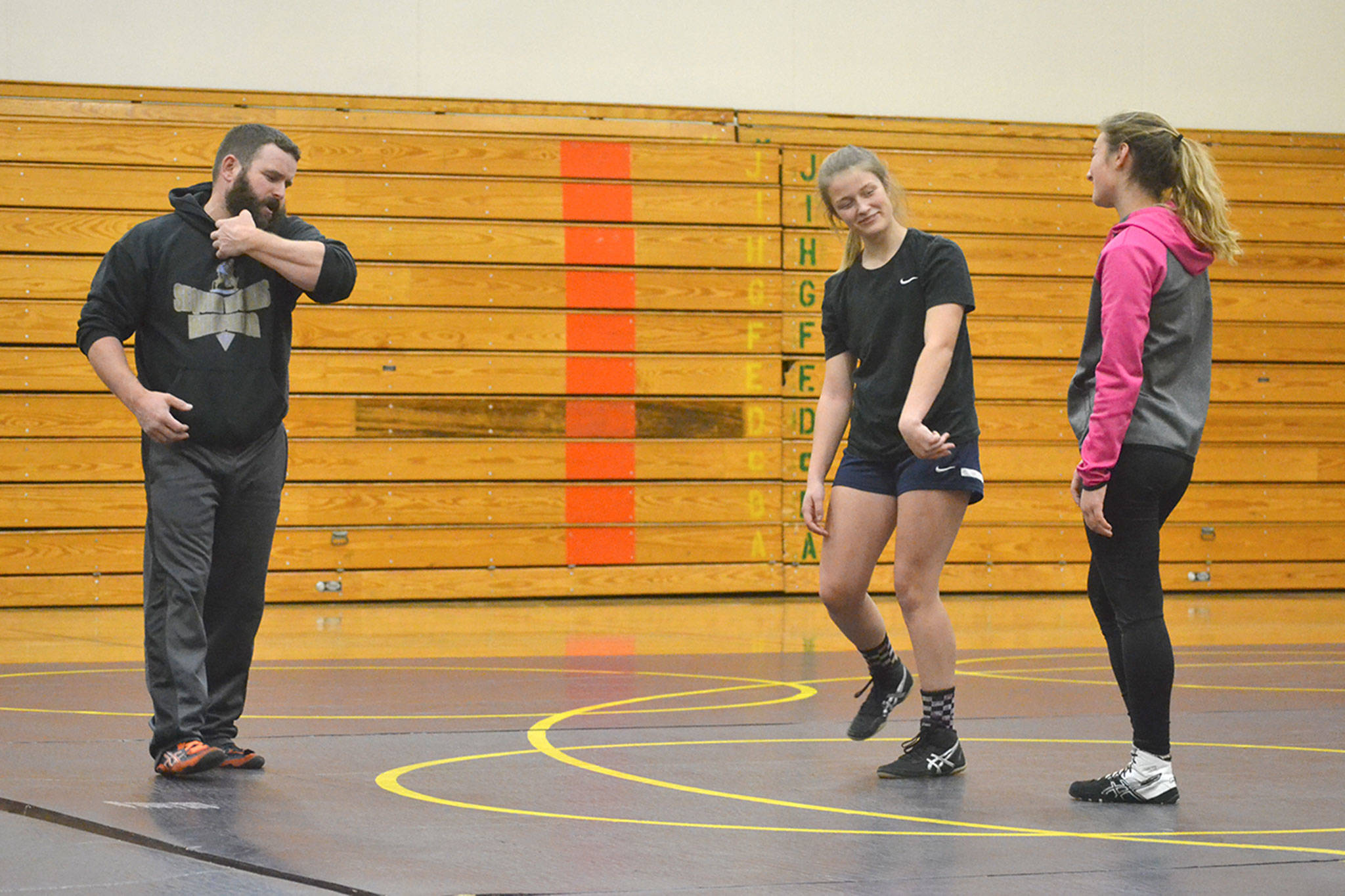Sequim wrestling coach Bill Schroepfer gives some advice to freshmen wrestlers Emily Dodson and Amara Sayer at a recent practice. They are two of 10 girls on the team this year. Sequim Gazette photo by Matthew Nash
