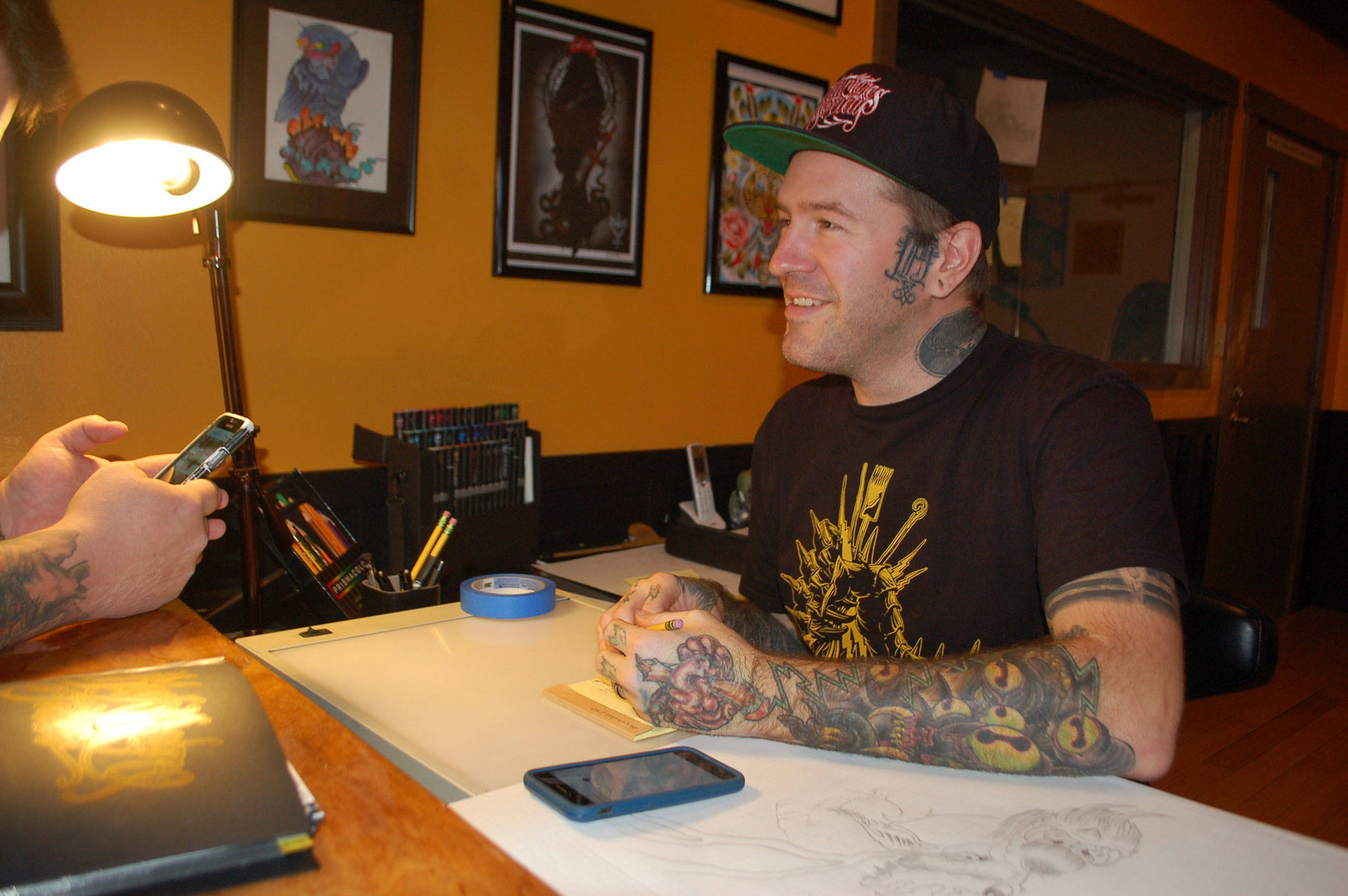 Professional tattoo artist Keith Dulin discusses tattoo design concepts with a client on the officially opening of his business Black Reign Tattoo on Nov. 25 in Sequim. Sequim Gazette photo by Erin Hawkins