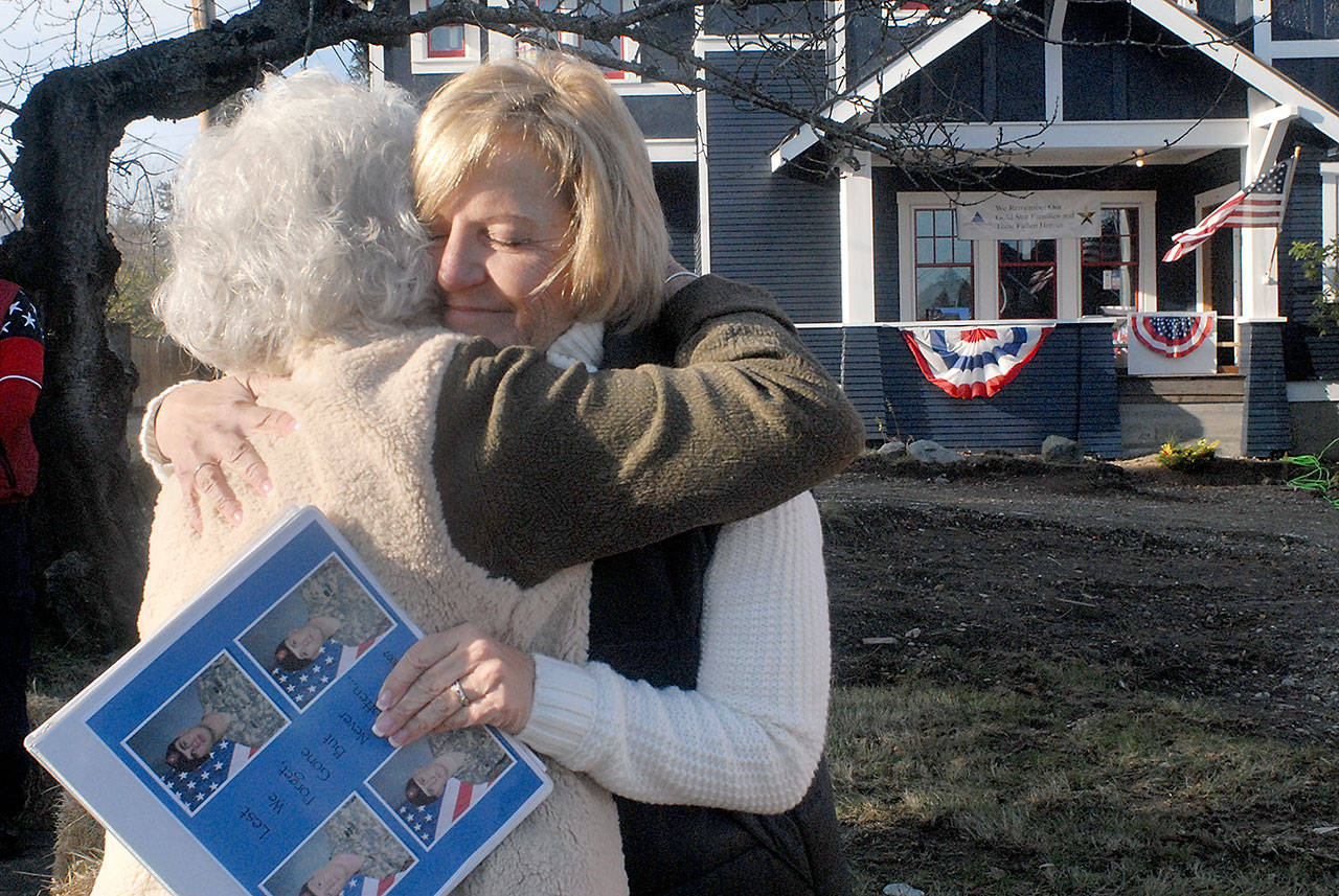 Gold Star mother Noala Fritz of Verdon, Neb., who travels with the “Remembering Our Fallen” memorial display, right, receives a hug from fellow Gold Star mother Betsy Reed Schultz, director of the Captain Joseph House Foundation in Port Angeles, during Friday’s opening ceremony for the memorial in the 1100 block of South Oak Street. (Keith Thorpe/Peninsula Daily News)