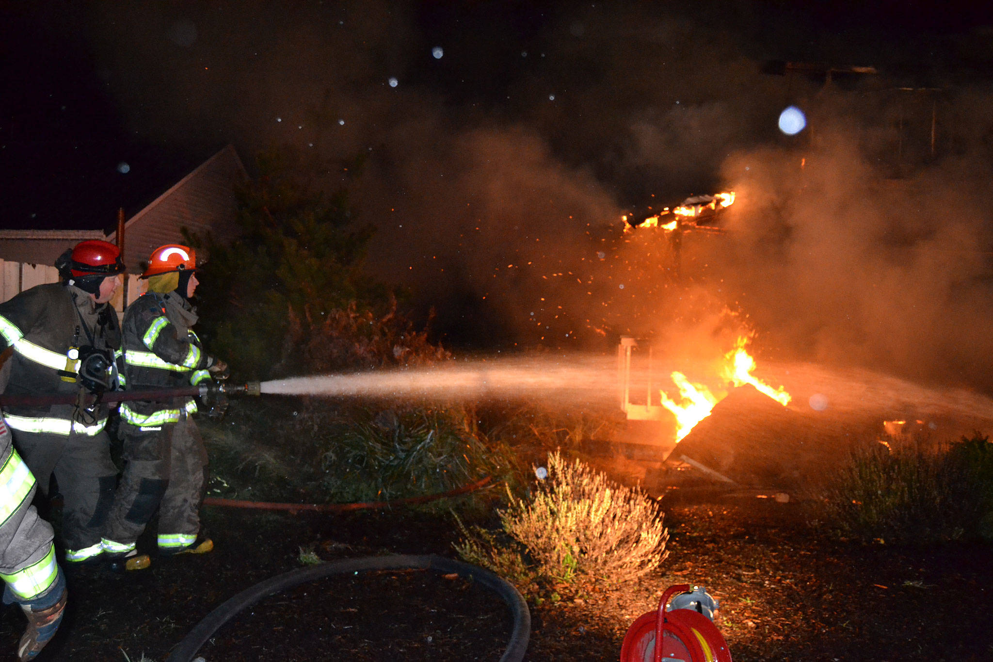 Captain Chris Turner with Clallam County Fire District 3 helps his son Tyler, an Explorer Scout with Post 1003, fight a house fire on Dec. 18 on 3 Crabs Road. Firefighters reported to the scene around 8:30 p.m. and extinguished it around midnight. Sequim Gazette photo by Matthew Nash