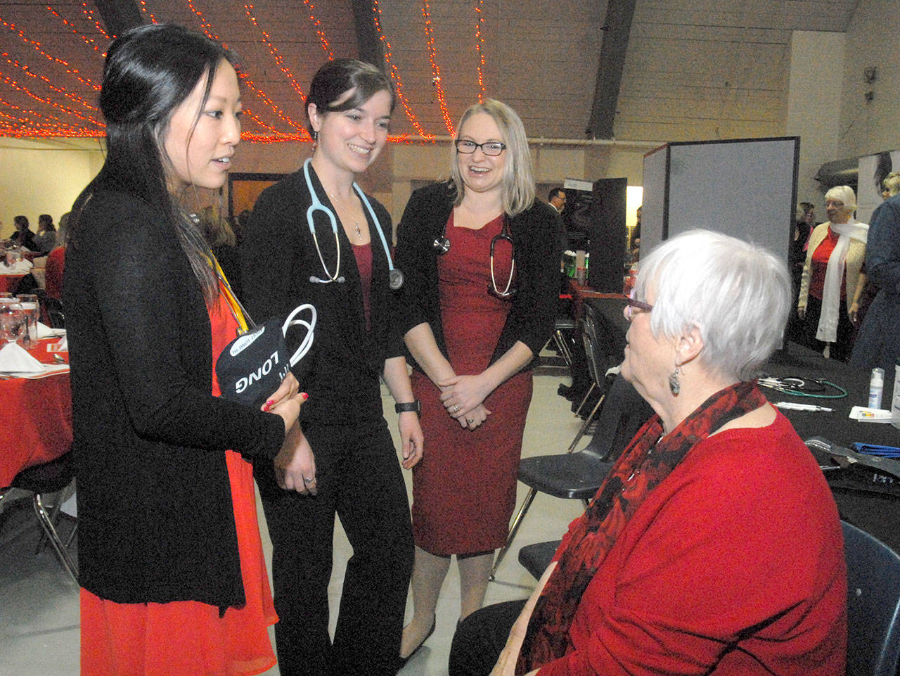 Keith Thorpe/Peninsula Daily News Olympic Medical Center workers, from left, exercise specialist Sherry Xiong, nuclear medical technician Brittany Payseno and cardiac sonographer Kerie Swegle talk with guest Dee Kurtz before the start of Friday’s 11th annual Red, Set, Go! Heart Luncheon at Vern Burton Community Center in Port Angeles. The charity event, hosted by the Jamestown S’Klallam Tribe, benefitted the Olympic Medical Center Foundation with goal of raising funds toward the purchase of a nuclear camera for cardiac stress testing.