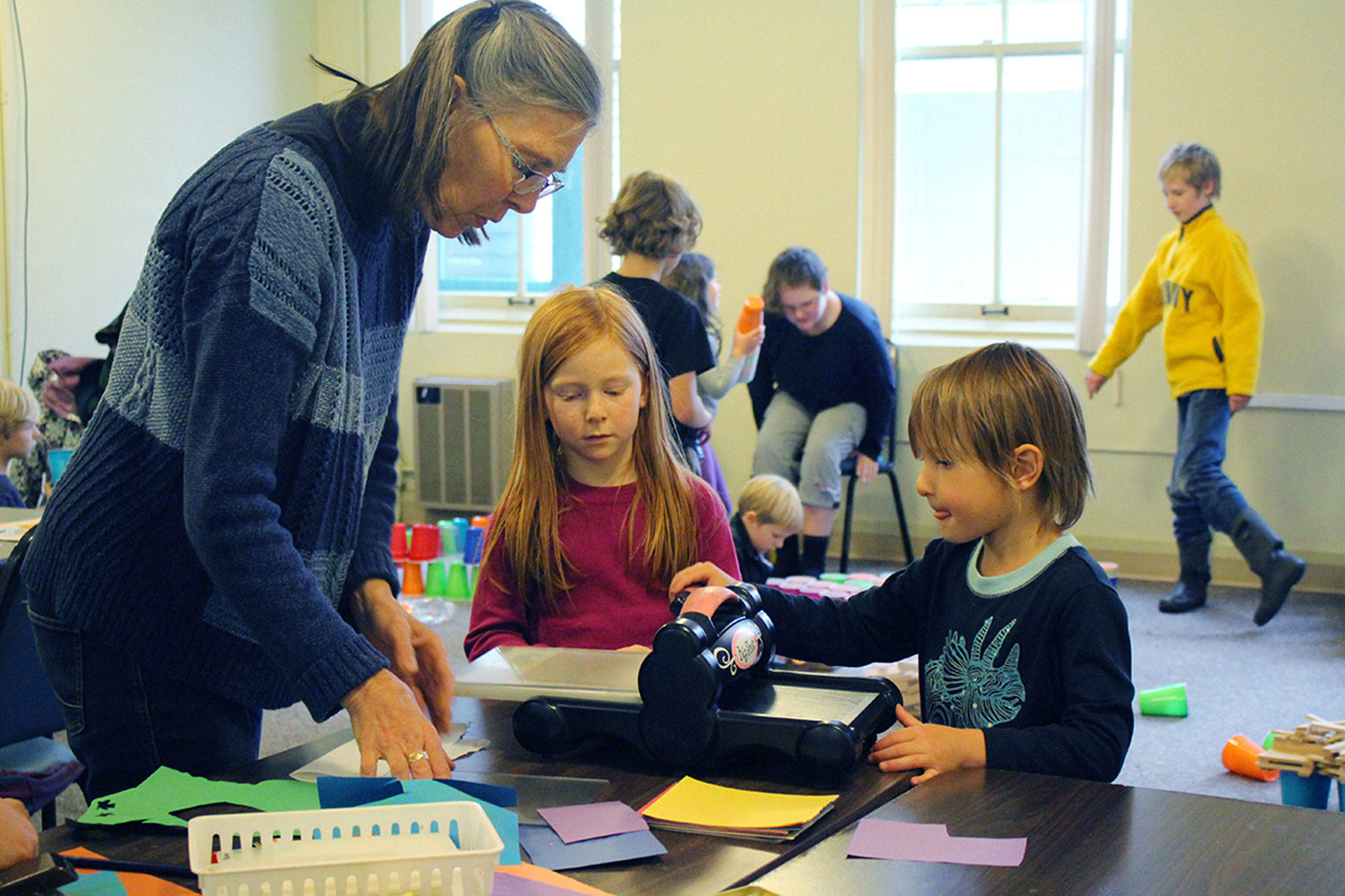 Lead teacher Frances Rice, left, with Alexis Frederickson and Eli Collins, demonstrating how to use a paper press in Art Studio on Fridays in Port Townsend. Submitted photo