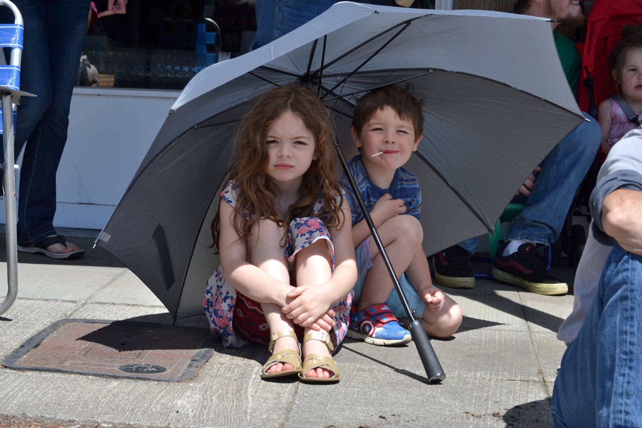 Paisley, 6, and Jonah, 5, Brockway of Sequim find some shade under an umbrella during the Grand Parade. Their family has come to the parade three years in a row. Sequim Gazette photo by Matthew Nash