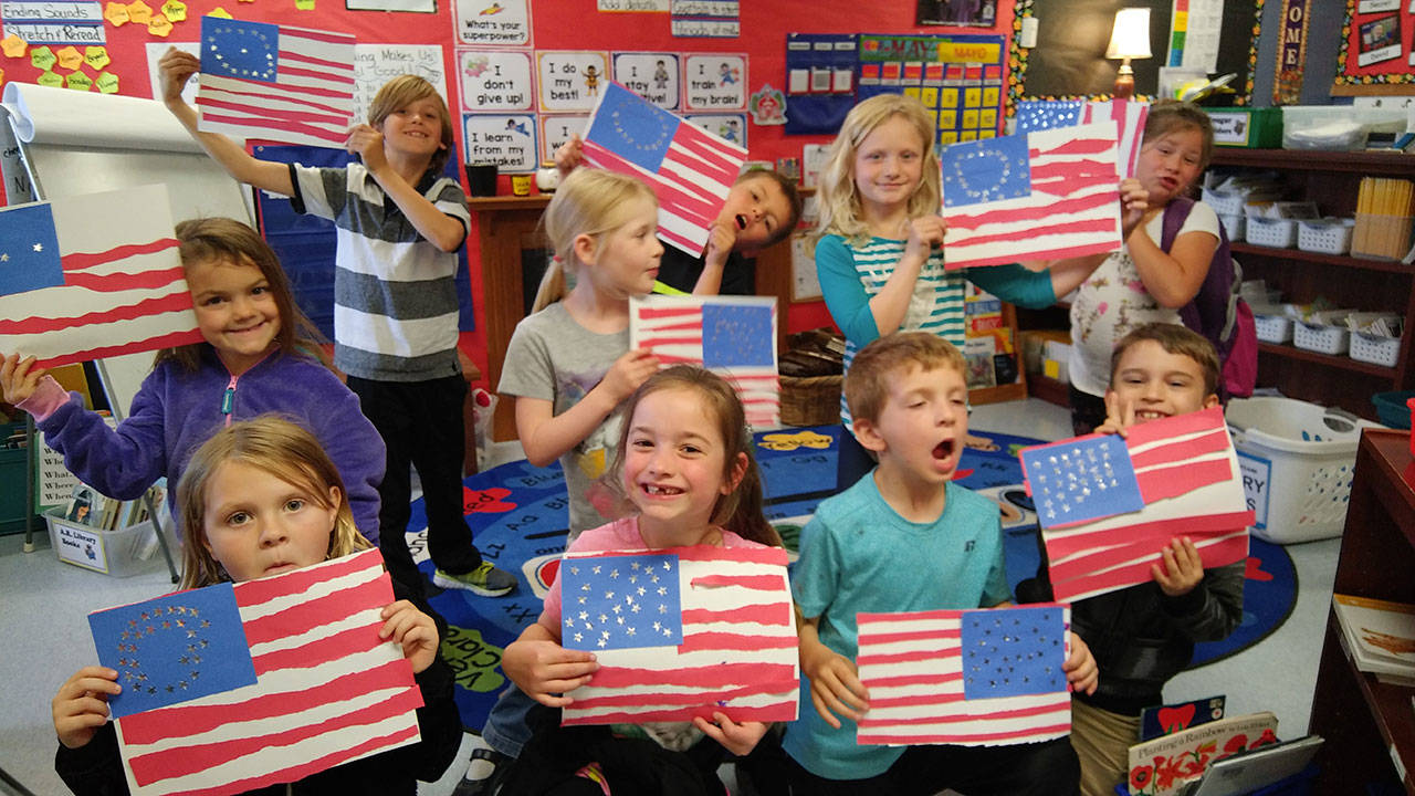 Students in teacher Ione Marcy’s first-grade class at Helen Haller Elementary School show off their American flags. Submitted photo