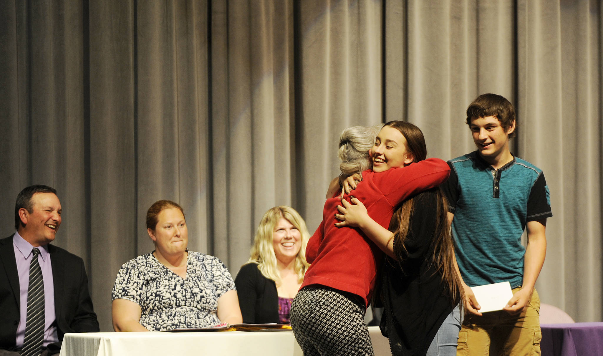 Mary Jane Duncan gives Bob Duncan Memorial Scholarships and hugs to SHS graduating seniors Chloe Ann Erickson and Levi Foy; from left, Sequim High School principal Shawn Langston and counselors Erin Fox and Melee Vandervelde look on. Sequim Gazette photo by Michael Dashiell