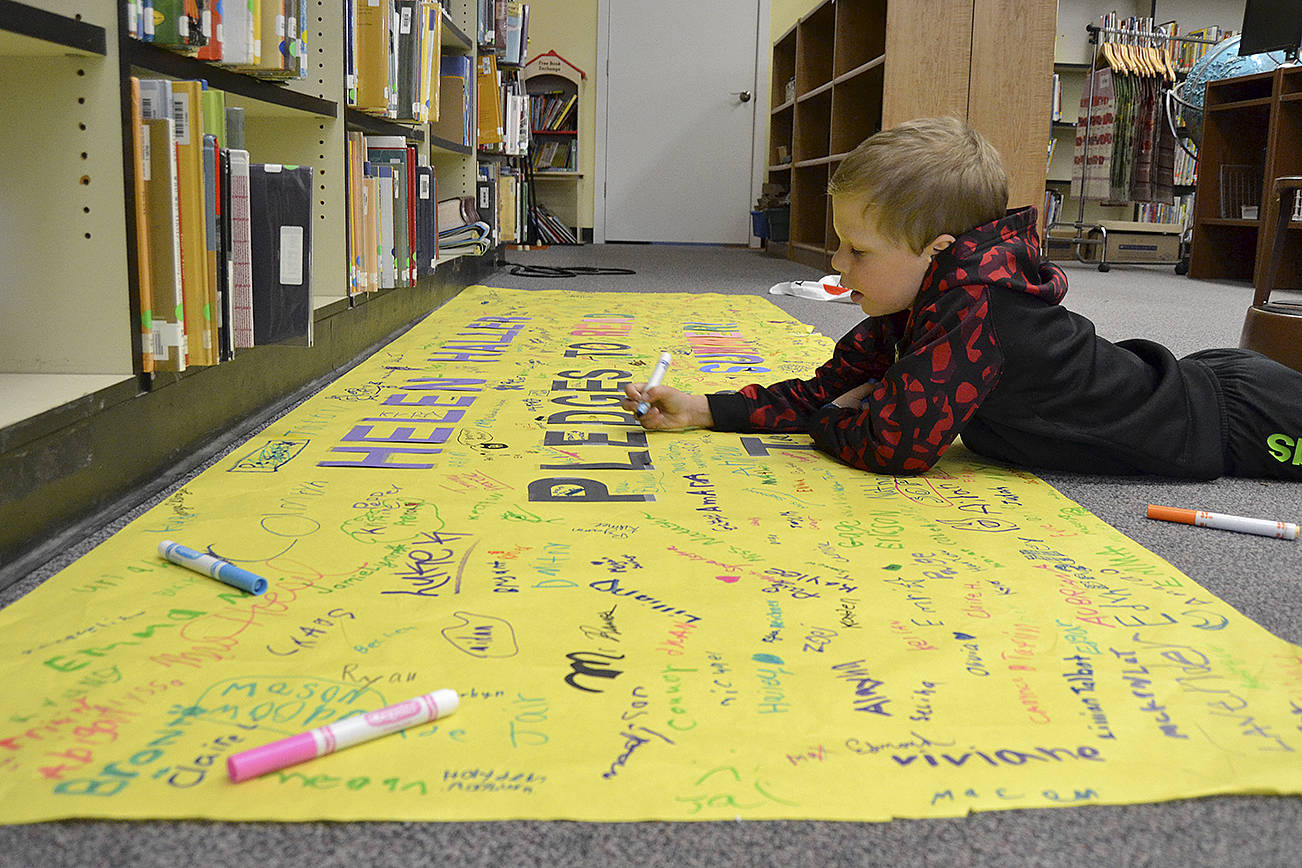 Brody Washburn, 7, signs his name pledging to read over the summer with help from the Six Books for Summer program at Helen Haller Elementary, which provided six new books for each student at the school. Sequim Gazette photo by Matthew Nash