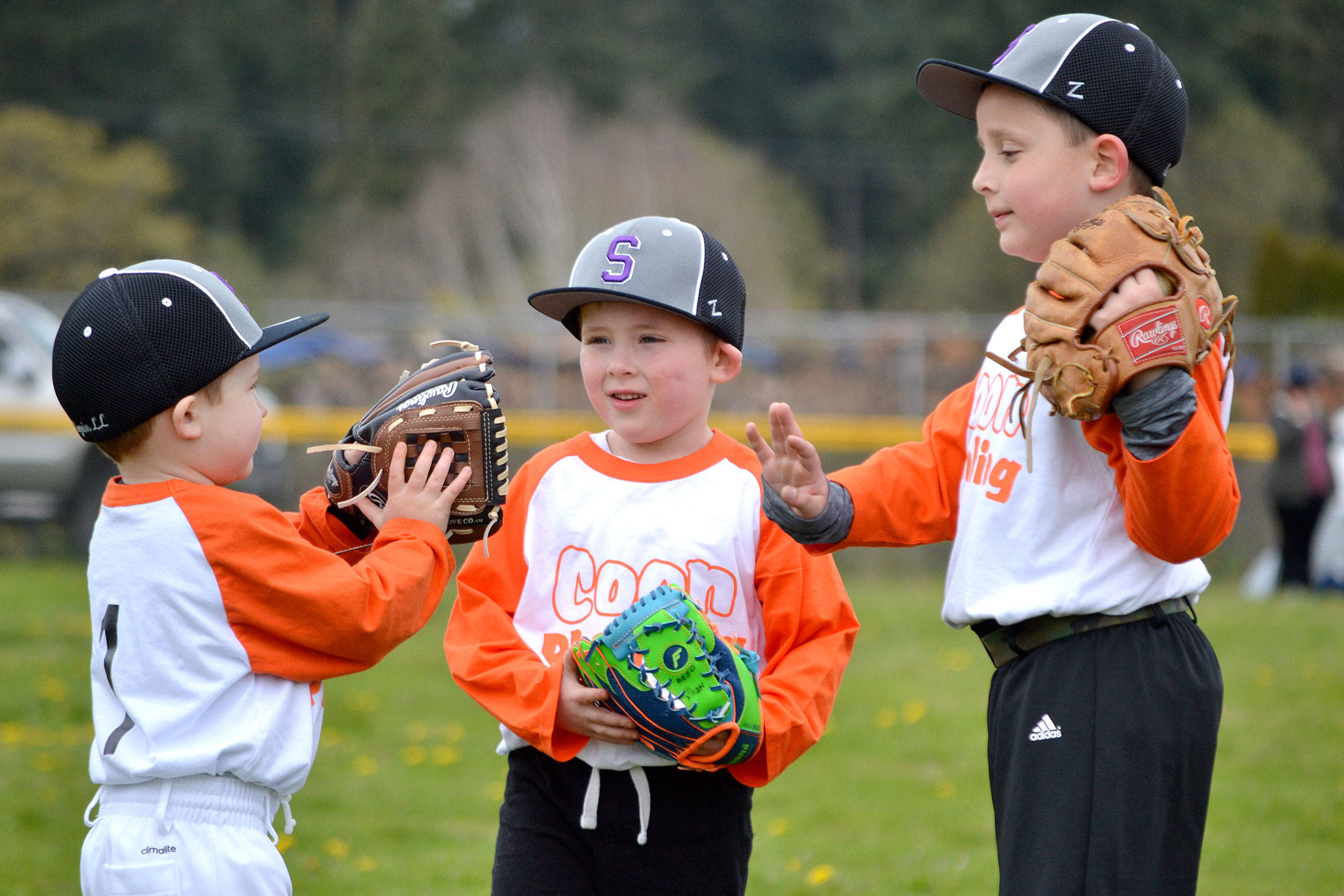 T-ball teammates for Coon Plumbing, from left, Parker Horst, Reed Nash and Cash Coon confer before a game about best strategies for catching a ball. Sequim Gazette photo by Matthew Nash