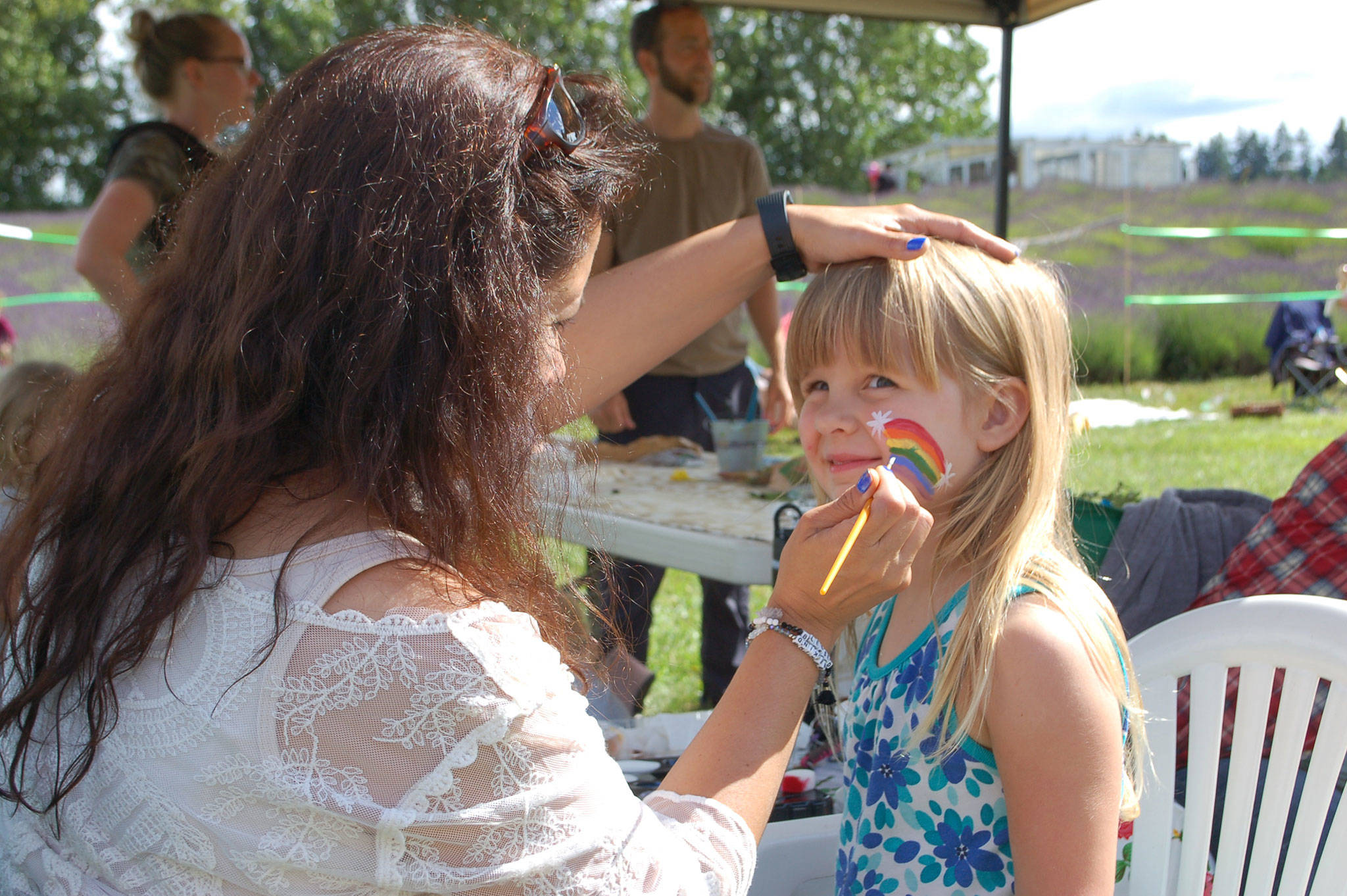 Emma Perry, 4, has her face painted by volunteer Ceci Buhrer at Olympic Nature Experience’s 5th annual picnic auction at Jardin du Soleil lavender farm on July 7. All proceeds of the program’s picnic and auction event benefitted Olympic Nature Experience. Sequim Gazette photo by Erin Hawkins