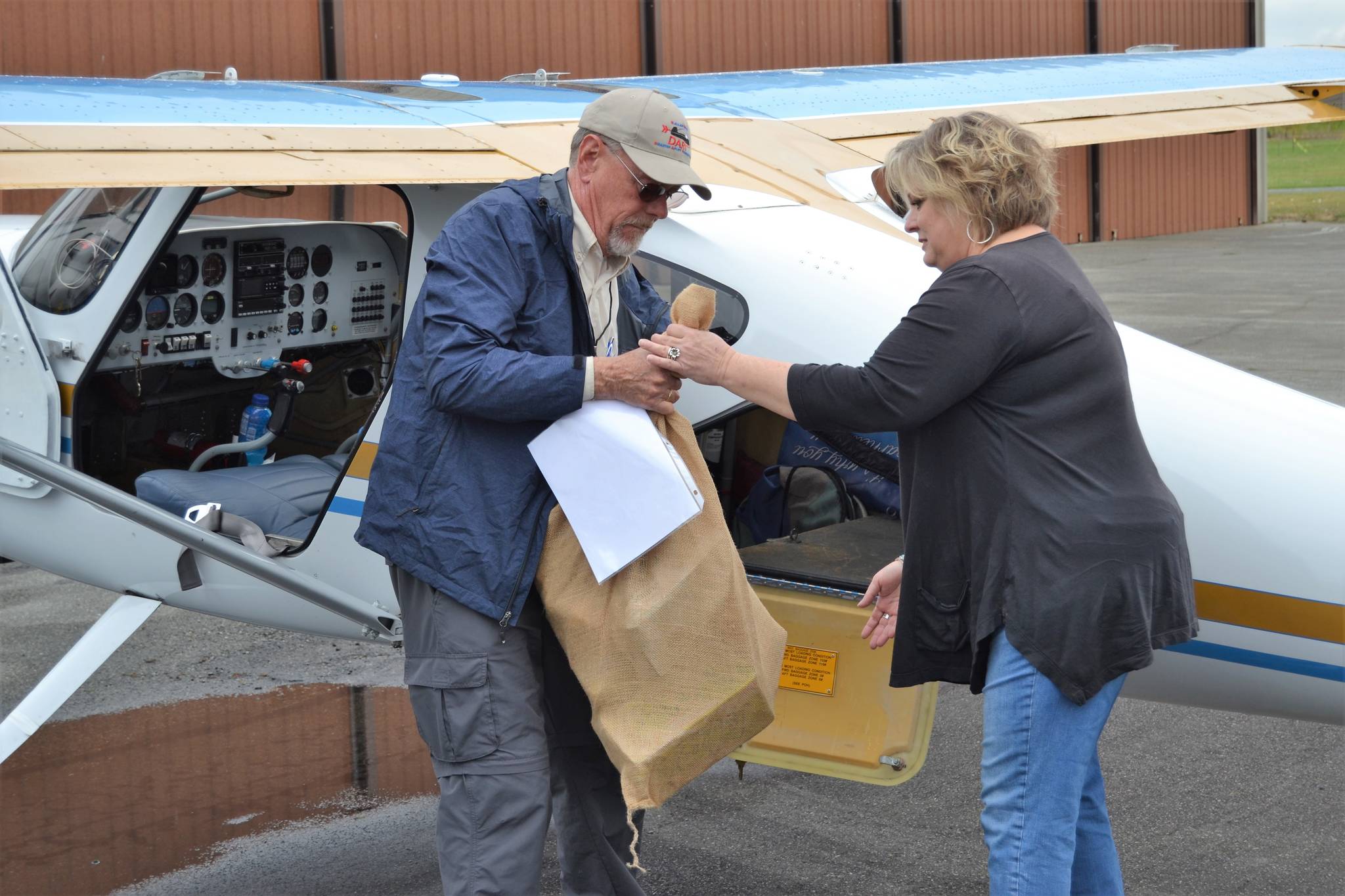 Ray Ballantyne, a volunteer with Disaster Aircraft Response Team hands a bag of food to Andra Smith, Sequim Food Bank executive director, on Sept. 15, at the Sequim Valley Airport.   Sequim Gazette photo by Matthew Nash