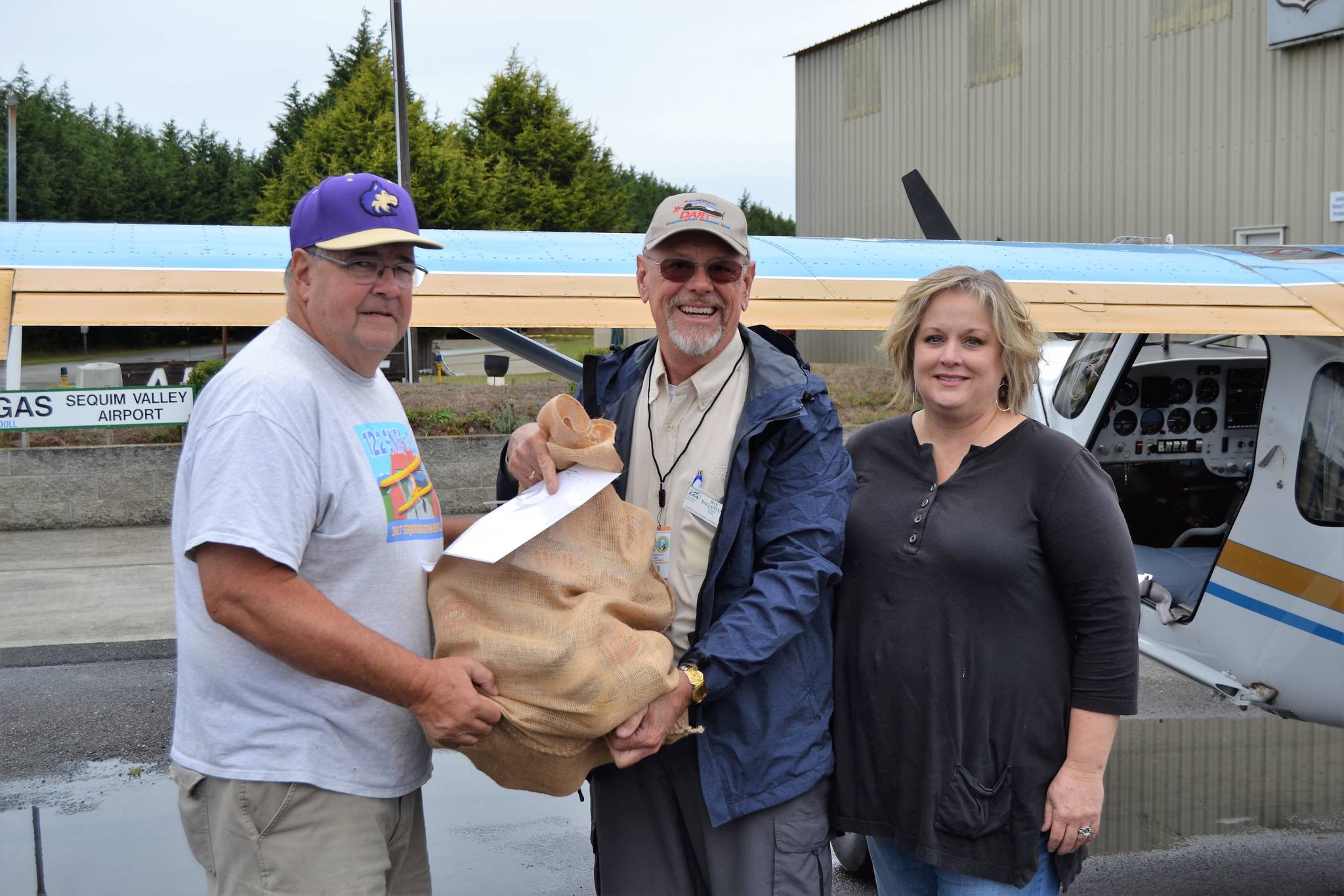 For the first of three trips, Ray Ballantyne, a volunteer with Disaster Aircraft Response Team (DART), in middle, hands a bag of food to Stephen Rosales, Sequim Food Bank board president, and Andra Smith, Sequim Food Bank executive director, on Sept. 15, at the Sequim Valley Airport. The event was a coordinated through DART to test a response plan following a catastrophic event and merged into a food drive, as well. Sequim Gazette photo by Matthew Nash