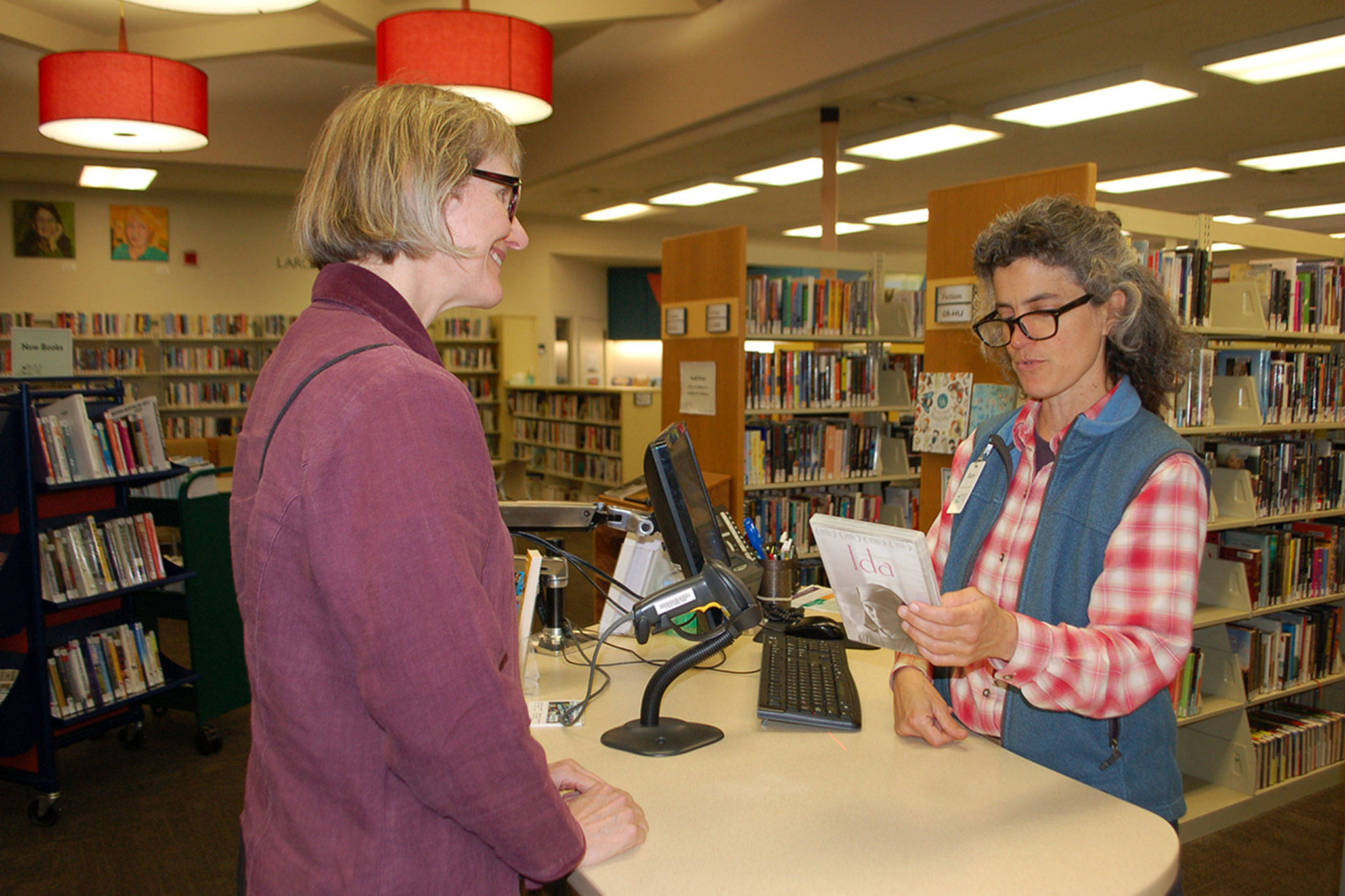 Sequim Library customer service specialist Mary Cote talks with Lindy MacLaine about a DVD at the Sequim Library on Sept. 21. Sequim Gazette photo by Erin Hawkins