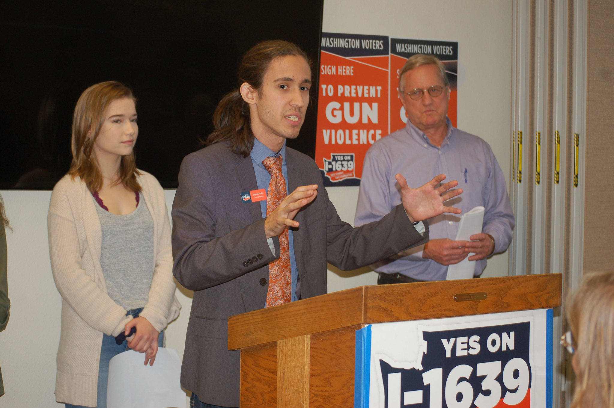 Stephen Paolini, campaign manager for “Yes” on Initiative 1639, center, with Port Angeles High School student Raven Sharpe and State Rep. Steve Tharinger (D-Port Townsend) looking on, addresses a crowd of supporters at the Sequim Library on Sept. 24. The initiative is a “comprehensive gun violence prevention measure” that will change the age to purchase semi-automatic assault rifles from 18-21, creates an enhanced background check to purchase semi-automatic assault rifles, creates secure storage practices, and makes buyers aware of risks associated with firearms. The measure goes to the General Election ballot on Nov. 6. Sequim Gazette photo by Erin Hawkins