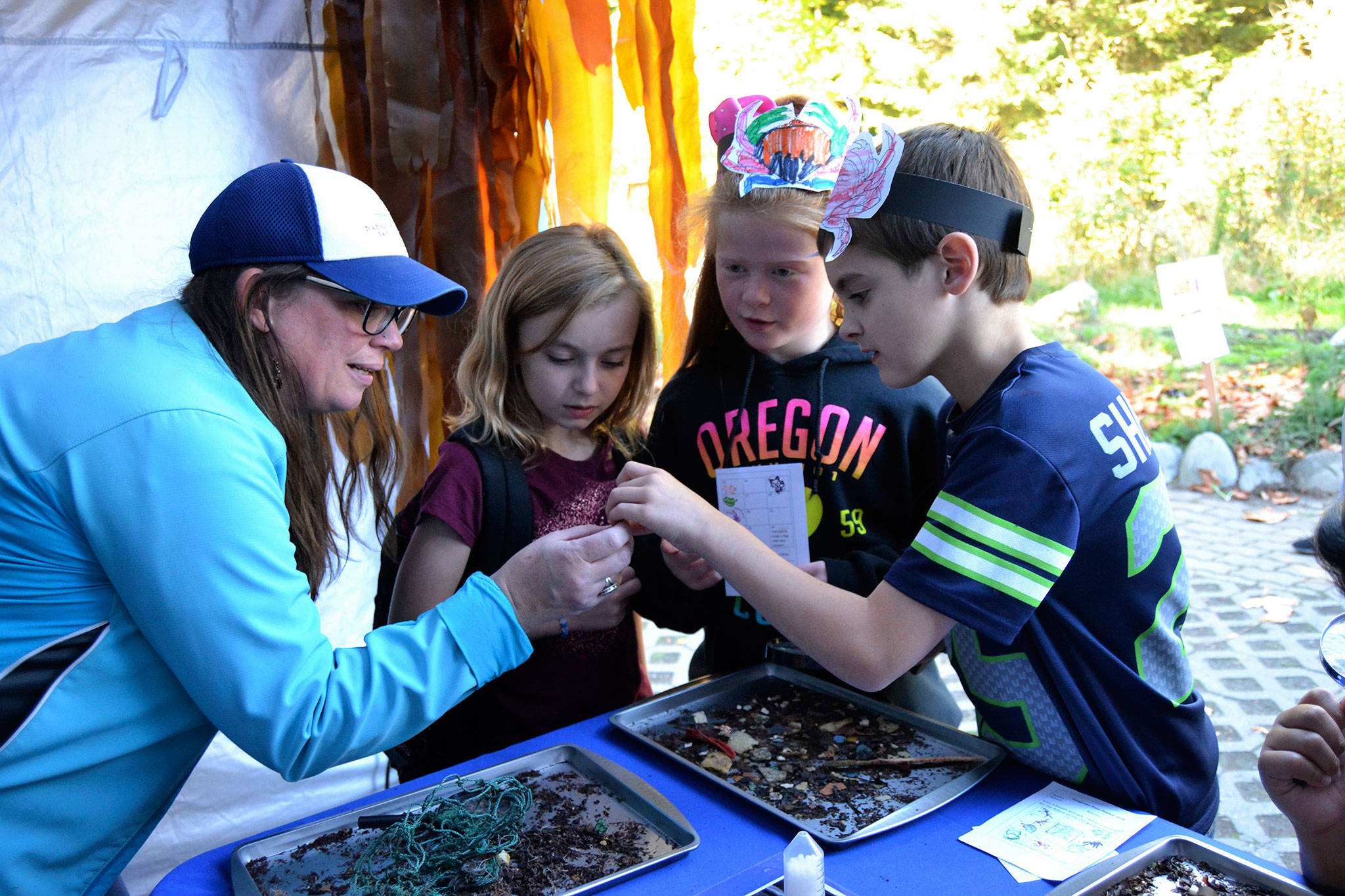 Nicole Harris, education and outreach specialist for the National Marine Sanctuary, speaks with students, from left, Annmarie Tillman, Paxtin Gagner, and Mikhail Brooks during the Dungeness River Festival. Sequim Gazette photo by Matthew Nash