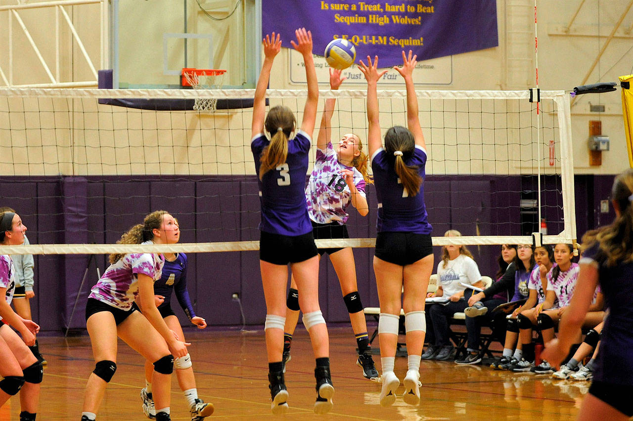 Sequim’s Annika Christiansen (18) looks to hit between the blocks of North Kitsap defenders Taylyn Boop (3) and Autumn Carver (7) in the Wolves’ five-game loss to the No. 1-ranked Vikings on Oct. 11. Sequim Gazette photo by Matthew Nash