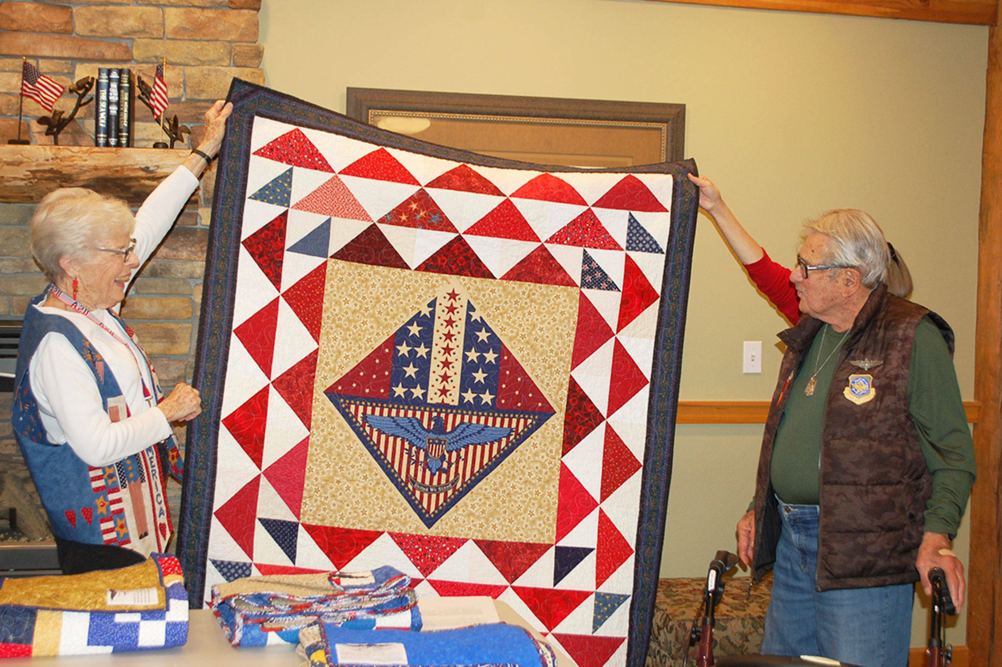 Barbara Hughes, a member of the quilting group “Grateful Grannies,” presents a quilt to Monte Mogi, a local Vietnam War veteran who served in the U.S. Air Force as a flight engineer, on Oct. 19 at the Lodge at Sherwood Village. Sequim Gazette photo by Erin Hawkins