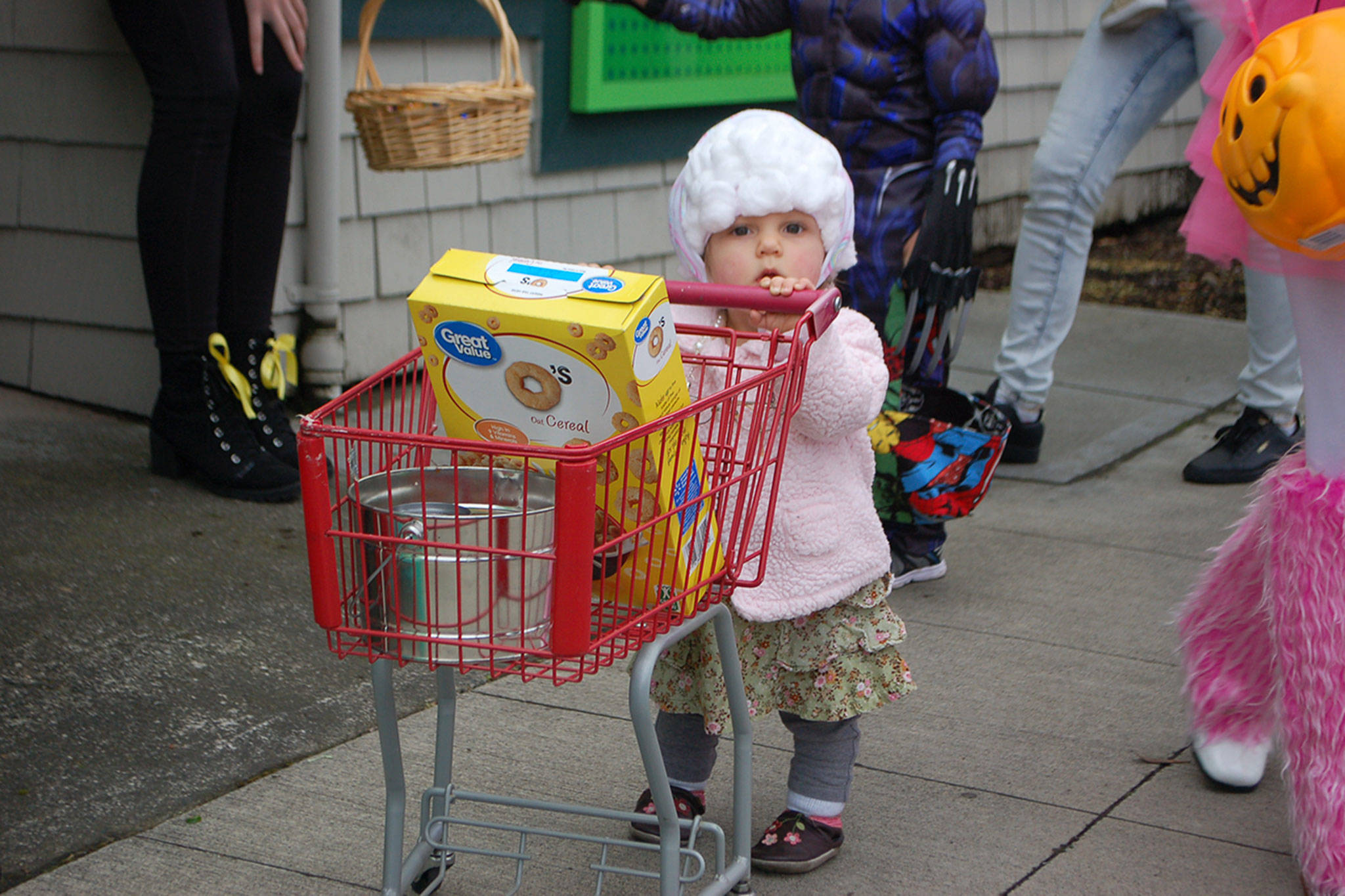 Elizabeth Treece, 14 months, of Sequim, dresses as a “shopping granny” as she pushes a tiny grocery cart with a bowl for candy while she trick-or-treats in downtown Sequim on Oct. 31. Sequim Gazette photo by Erin Hawkins