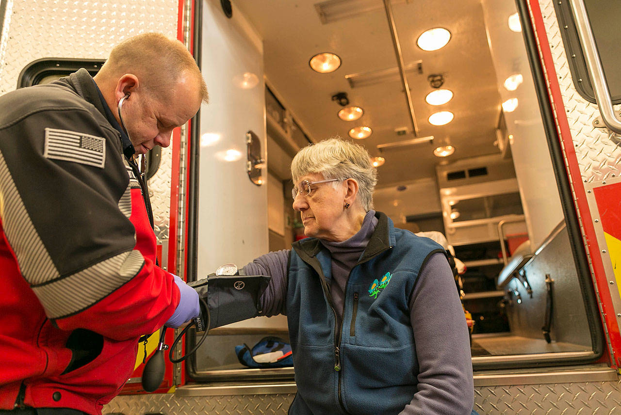 John McIntyre, a Clallam County Fire District 3 firefighter/EMT, gives a blood pressure test to Sequim community member Priscilla Hudson. Photo by Linda BarnfatherFire