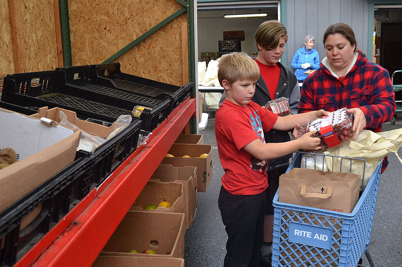 Corrine Wallen of Sequim with her sons Drew, 9, and Aaron, 12, select some healthy options for their Thanksgiving meal at the Sequim Food Bank, Drew said he loves eating turkey and Aaron loves “slobbering pumpkin pie in whipped cream.”