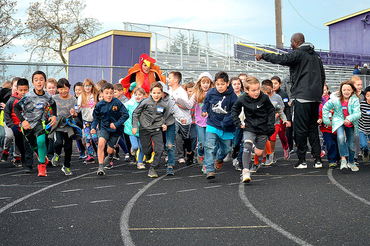 Physical education teacher Joclin Julmist starts students off for their Turkey Trot on Nov. 21 at the Sequim School District athletic field. Students ran/jogged/walked after family and friends donated to Helen Haller Elementary’s “Six Books for Summer” program and purchasing a rock-climbing wall. Sequim Gazette photo by Matthew Nash