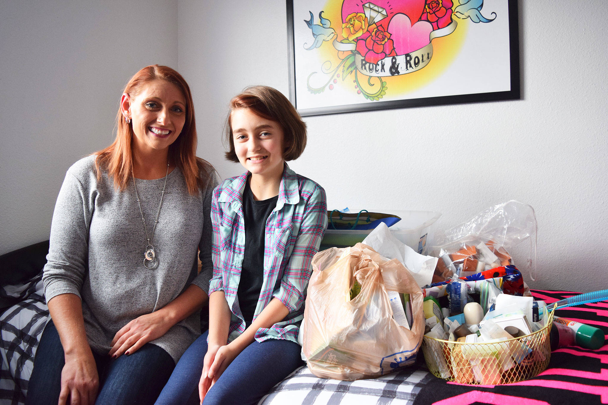 Anna Jensen, left, and her daughter River Jensen, 12, sit in their Sequim home with bags of toiletries River is collecting to donate to homeless individuals, shelters and food banks in December. Sequim Gazette photo by Erin Hawkins