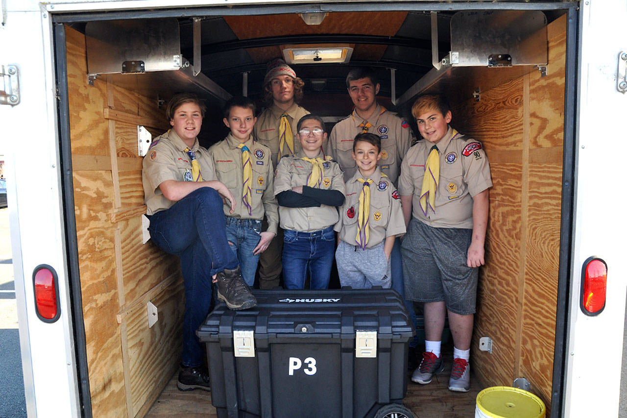 Boy Scouts with Troop 90 in Sequim stand inside the trailer that a thief or thieves broke into sometime last month and took about $900 in camping equipment. Troop leaders seek any support in replacing the items and in the mean time, scouts, from left, Aaron Wallen, 12, James Smith, 12, Connor Gosset, 17, Hunter Halverson, 13, Cayden Beauregard, 12, Beau Halverson, 15, and Shane Tenneson, 13, helped customers with carts and collecting blankets at Grocery Outlet on Dec. 8. Sequim Gazette photo by Matthew Nash
