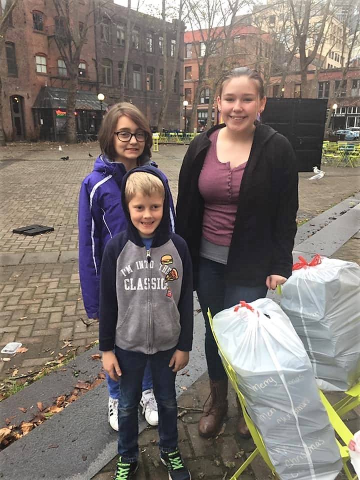 River Jensen, left, started sharing toiletry gift bags on Dec. 15 with help from her brother Canyon and cousin Grace in Seattle’s Pioneer Square. It’s the third year she’s collected and donated gift bags to homeless and at-risk individuals in Seattle and on the Olympic Peninsula. Photo courtesy of Dana Jensen