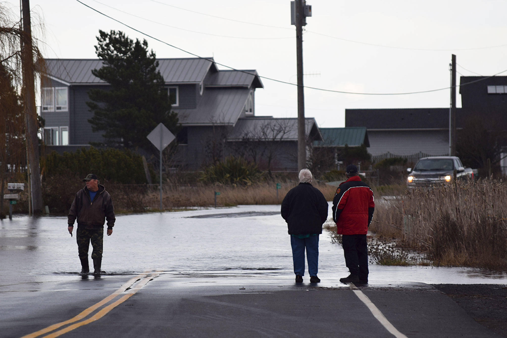 Dwayne Pettett, a nearby resident of 3 Crabs Road, left, wades through about 1 foot deep of water on 3 Crabs Road after high tides and storm surge caused water to flood parts of the area around noon on Dec. 20. Sequim Gazette photo by Erin Hawkins