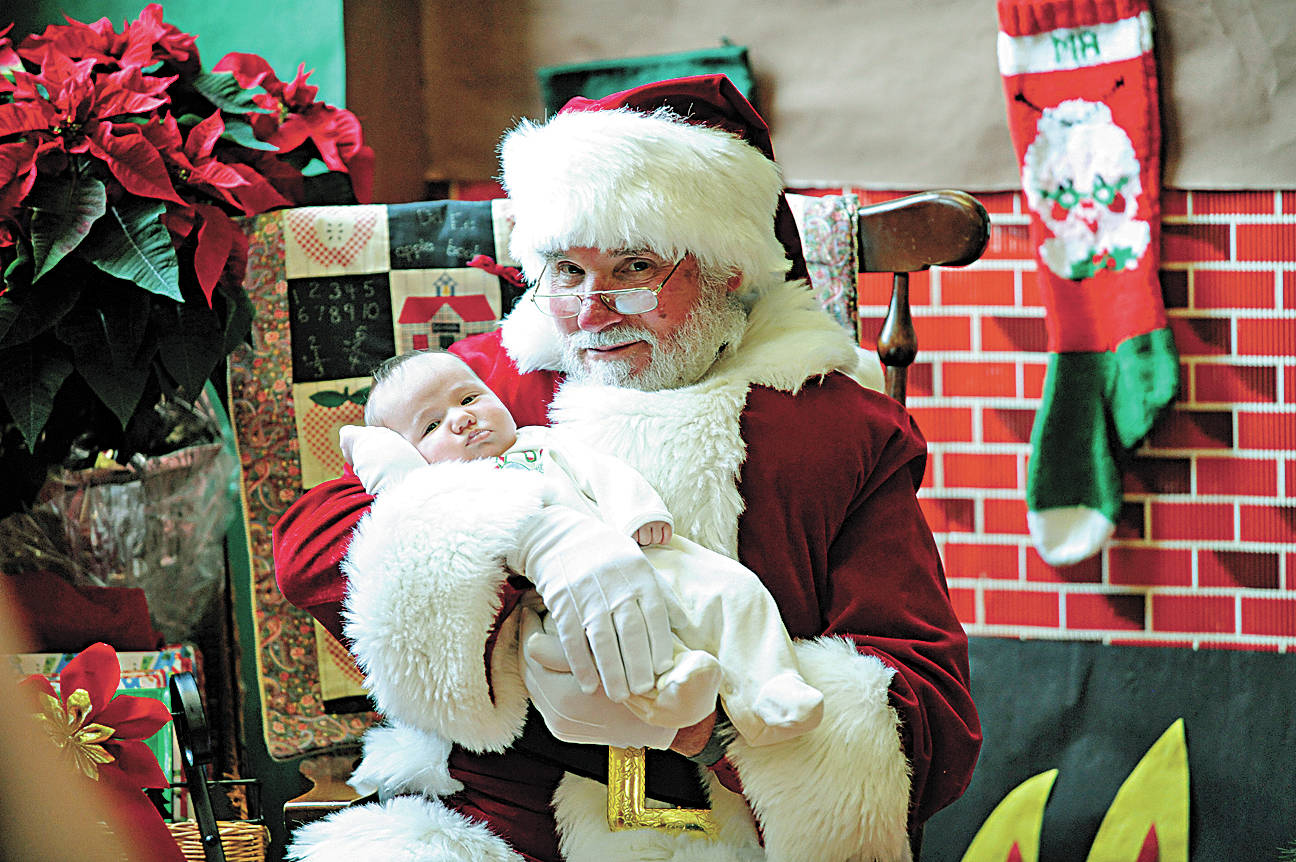 Walt Schubert, who portrayed Santa Claus at numerous Sequim civic events through the years, holds then 7-month-old Lilianna Lapp at a First Teacher Winter Celebration in December of 2010. Schubert, former city councilor and mayor, died on Dec. 22. Sequim Gazette file photo by Michael Dashiell