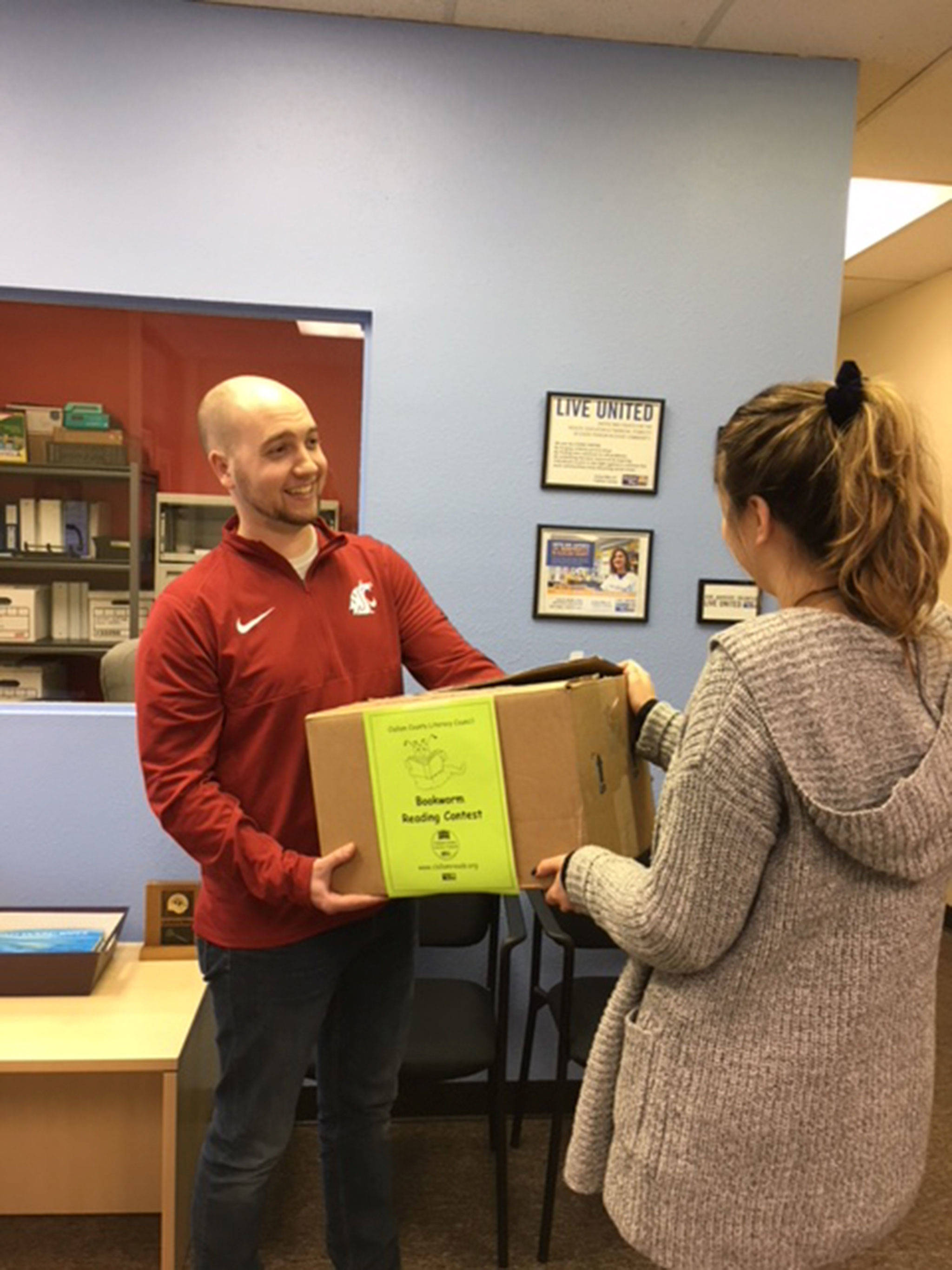 Travis Simmons, United Way representative for the Clallam County Literacy Council, provides a teacher a box of supplies from the Council for a reading contest. Each year, the Literacy Council offers the Bookworm Reading Contest for schools to host across the county. Submitted photo
