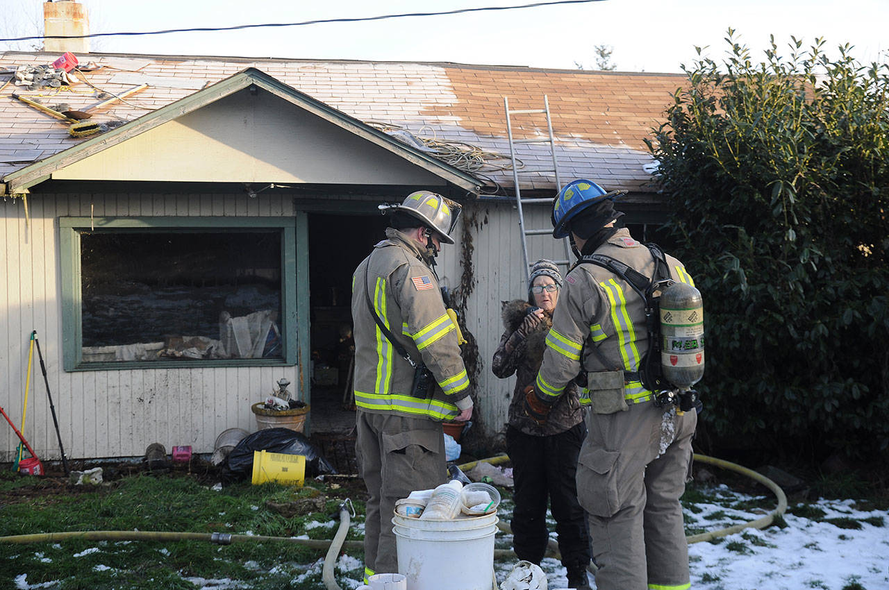 Clallam County Fire District 3 personnel talk with Pearl Williams, one of two residents living in a home near Carlsborg that was damaged by an early morning fire Thursday. Williams was not home at the time of the fire and no people were hurt in the incident, district officials said. Sequim Gazette photo by Michael Dashiell