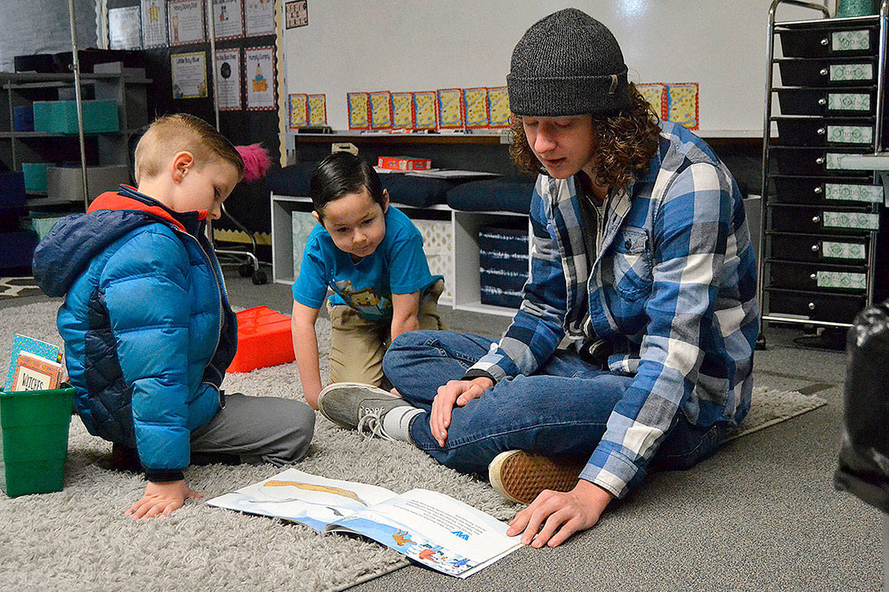 Sequim High junior Mike McAleer reads to kindergartners Aden Uhlig and Will Allen in Melissa Novak’s class on March 1 for Read Across America Day at Helen Haller Elementary. Sequim Gazette photo by Matthew Nash