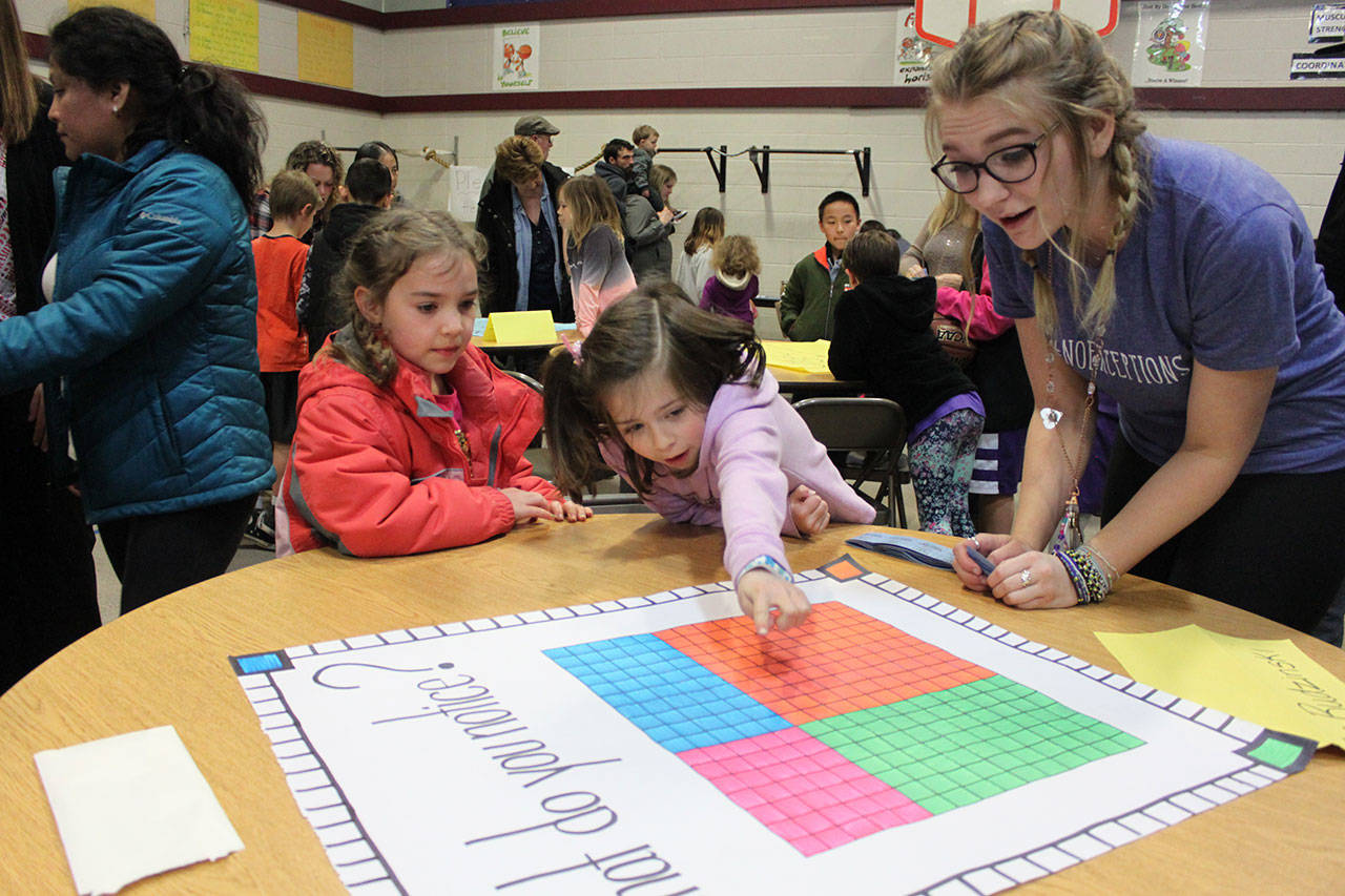 Greywolf first-graders Rosalie Sly-Hobson, center, and Harper Hilliker-McCloskey participate in Greywolf’s recent Math Night event, as teacher Lora Rudzinski assists. Submitted photo