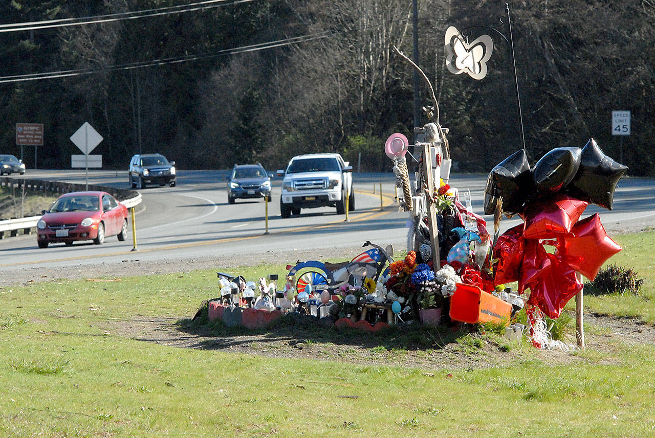 Traffic last week passes a roadside memorial to Brooke Bedinger, who died in a motorcycle wreck on U.S. Highway 101 at Morse Creek near Port Angeles on June 21. The state House has proposed funding for a barrier but the state Senate budget does not include the $2.5 million project. Photo by Keith Thorpe/Peninsula Daily News