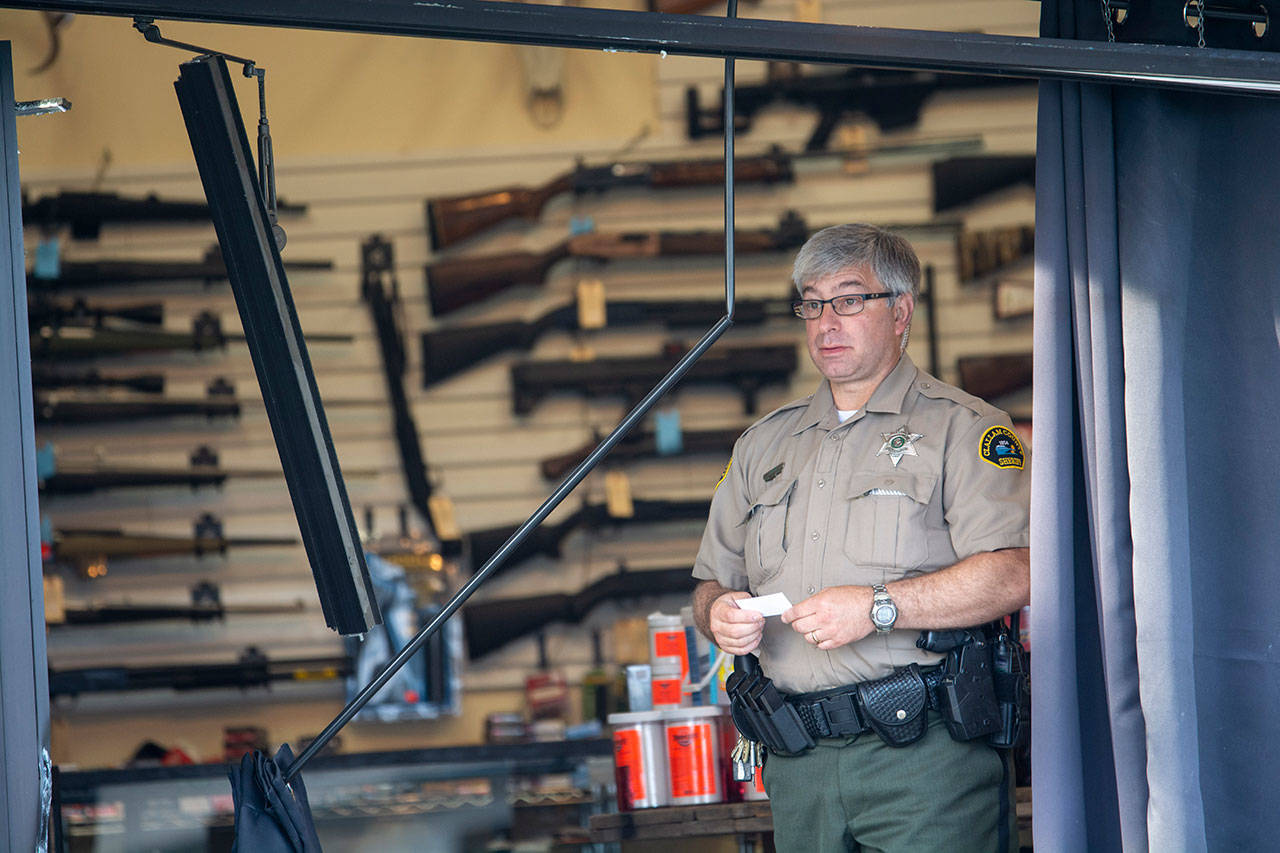 Clallam County Sheriff’s Deputy Bill Cortani stands in FREDS Guns in Sequim on Sunday morning after someone used heavy equipment to break into the store overnight. (Jesse Major/Peninsula Daily News)