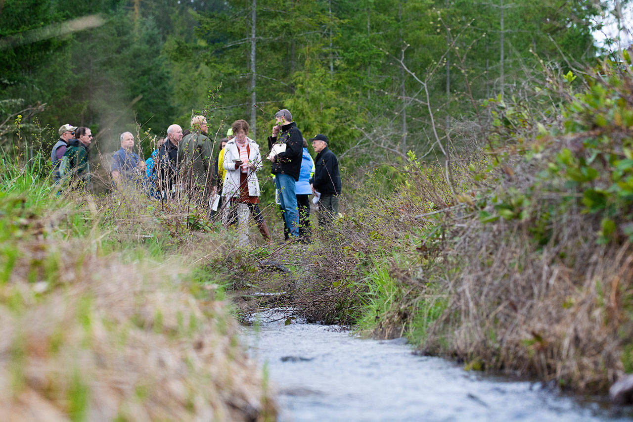 Irrigation water passes under officials from the City of Sequim and Clallam County as they tour the future site of the Dungeness Off-Channel Reservoir on April 22. Photo by Jesse Major/Peninsula Daily News
