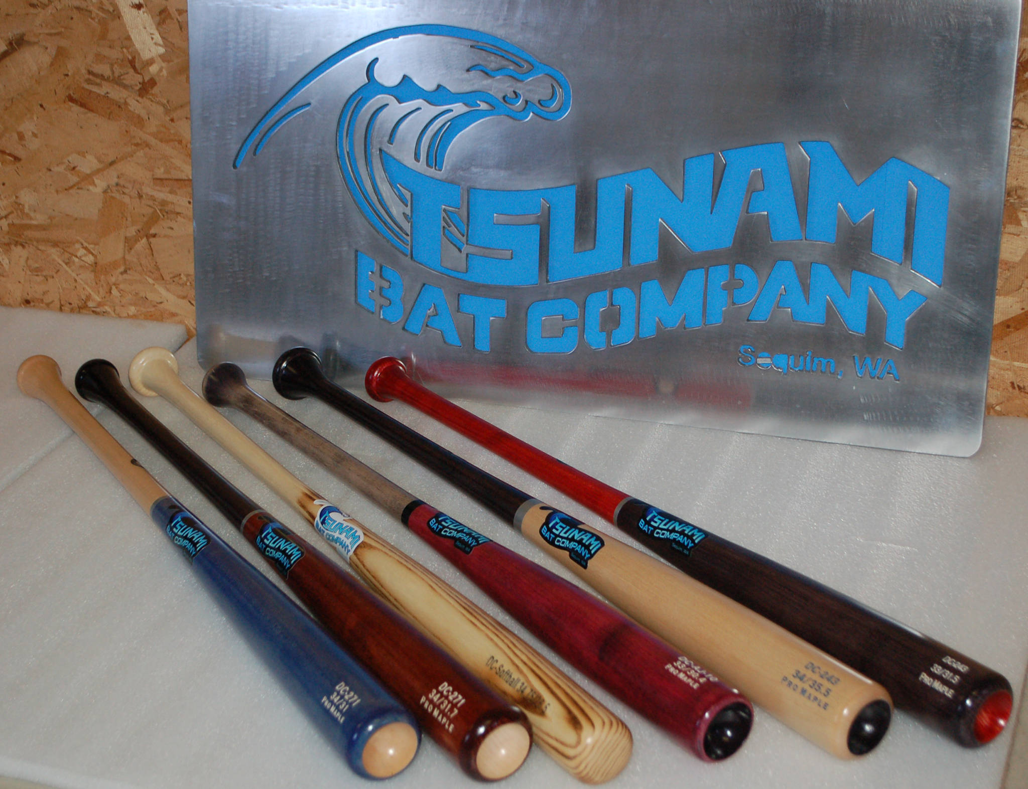 Several finished Tsunami Bat Company bats on display with the Sequim company’s sign. Sequim Gazette photo by Conor Dowley.