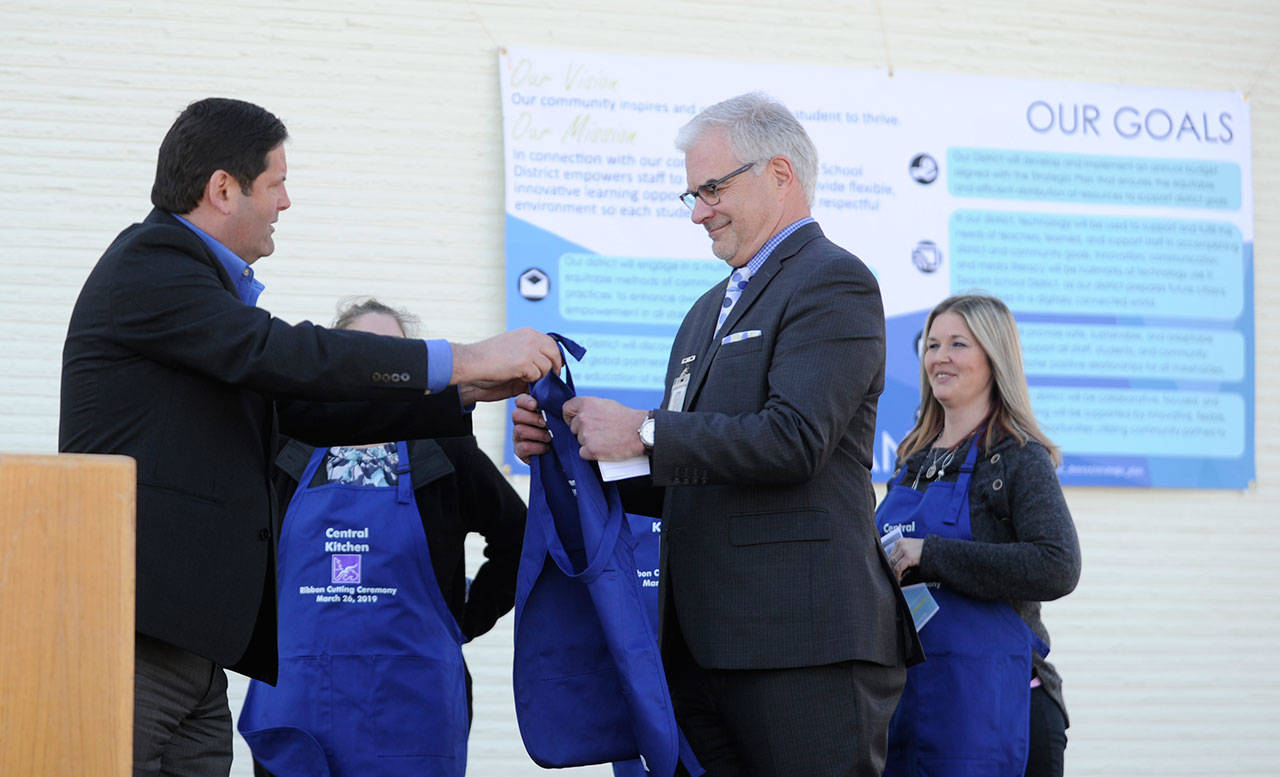 Sequim schools superintendent Gary Neal, right, receives an honorary apron from Bernie O’Donnell, vice president/Northwest area manager for Vanir, as school representatives and officials celebrate the opening of the Sequim School District’s new central kitchen on March 26. Neal announced this week he is resigning his superintendent position effective June 30, and will take a position with Vanir Construction Management, Inc., the firm that oversaw the central kitchen project along with demolition of the unused 1950s portion of the community school. Sequim Gazette file photo by Michael Dashiell