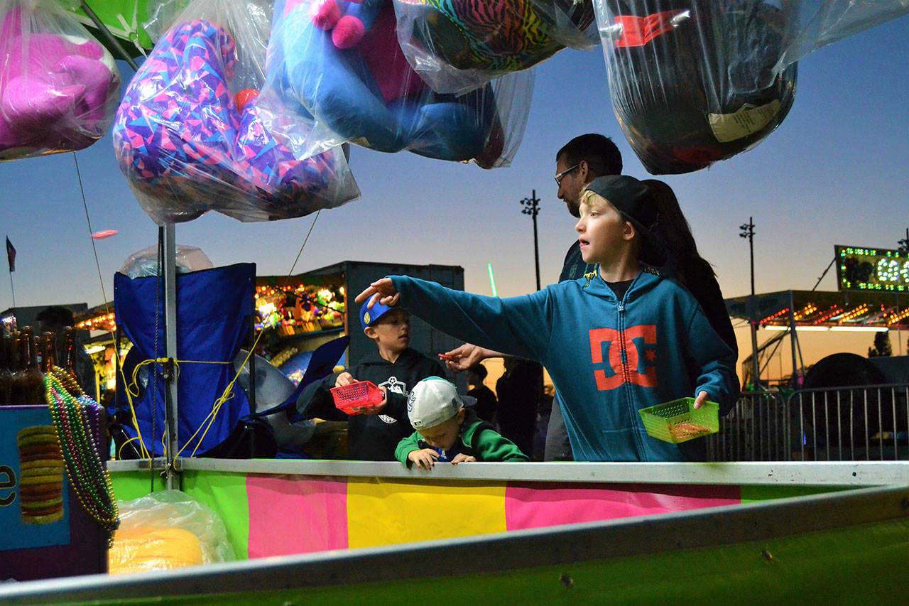 Blake Bacchus makes a throw in the ring toss as his brothers Nolan and Roman wait their turn at the 2018 carnival. It continues this year May 9-12. Sequim Gazette file photo by Matthew Nash