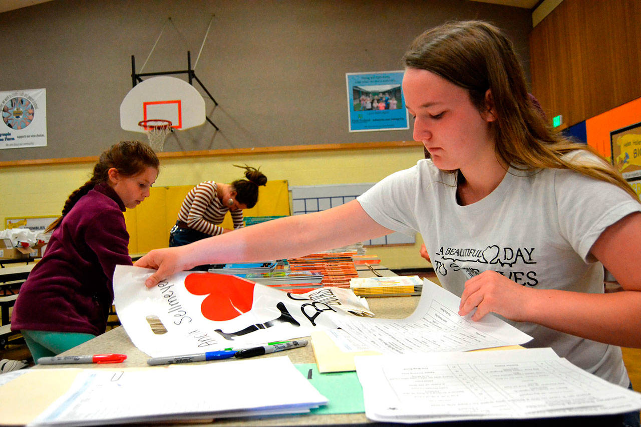Amanda Weller, 15, writes names on bags for Helen Haller Elementary’s Six Books for Summer program on May 22. Weller was one of many Sequim High students with its Interact Club helping students and parent volunteers bag and sort thousands of books. Sequim Gazette photo by Matthew Nash