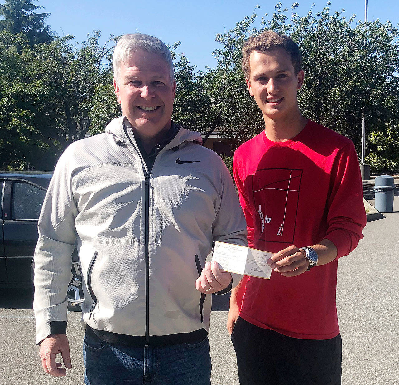 Bill Shea, Director of Golf/general manager at The Cedars at Dungeness, presents funds raised from the 2019 Golf 4 Grads tournament to Liam Payne, Sequim High School senior class vice president. Submitted photo