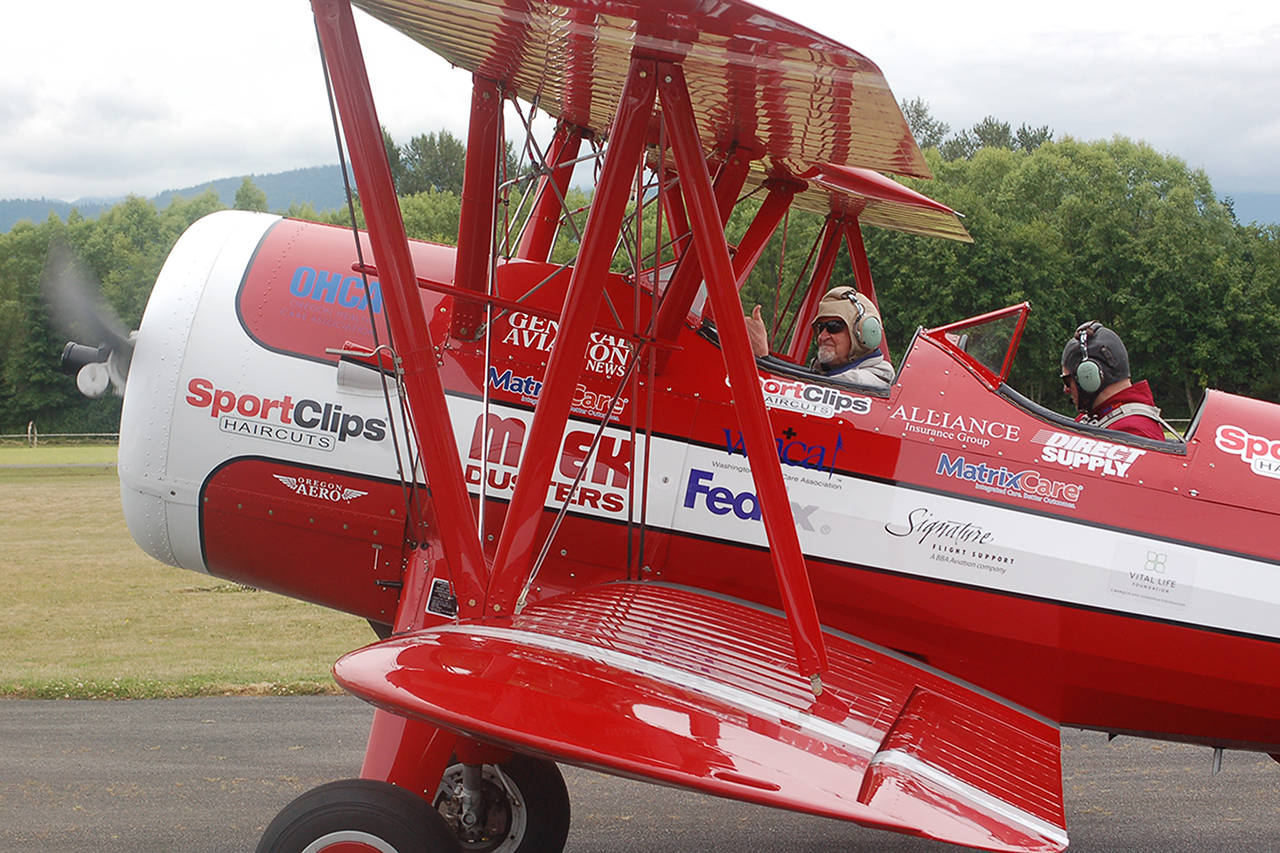 Clint Cawley of the Ageless Aviation Dreams Foundation taxis the “Red Stearman” biplane in at the Sequim Valley Airport as retired Air Force veteran Ken Leuthold gives an emphatic thumbs-up. Sequim Gazette photo by Conor Dowley.