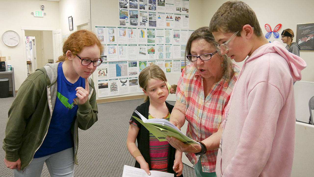 From left, Grayce Houle, Maia Brewer, director Bonne Smith and Hunter Halverson work on lines for the upcoming Olympic Theatre Arts production of “The Reluctant Dragon.” Photo courtesy of Olympic Theatre Arts