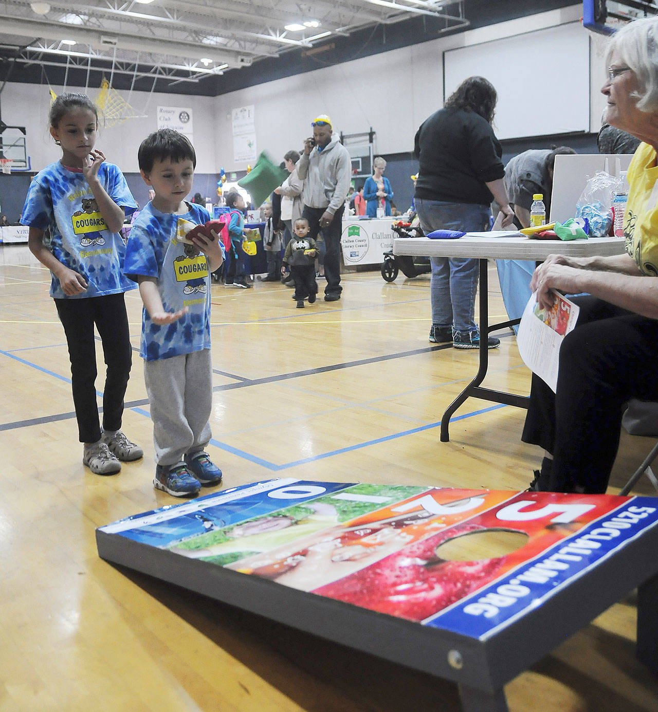 At the 2018 Back to School Fair, Charlie Petersen, 5, and Chelsea, 8, learn a bit about healthy living while playing a beanbag toss game at the Olympic Peninsula Healthy Community Coalition booth with help from volunteer Patty Shoop (right). Sequim Gazette file photo by Michael Dashiell