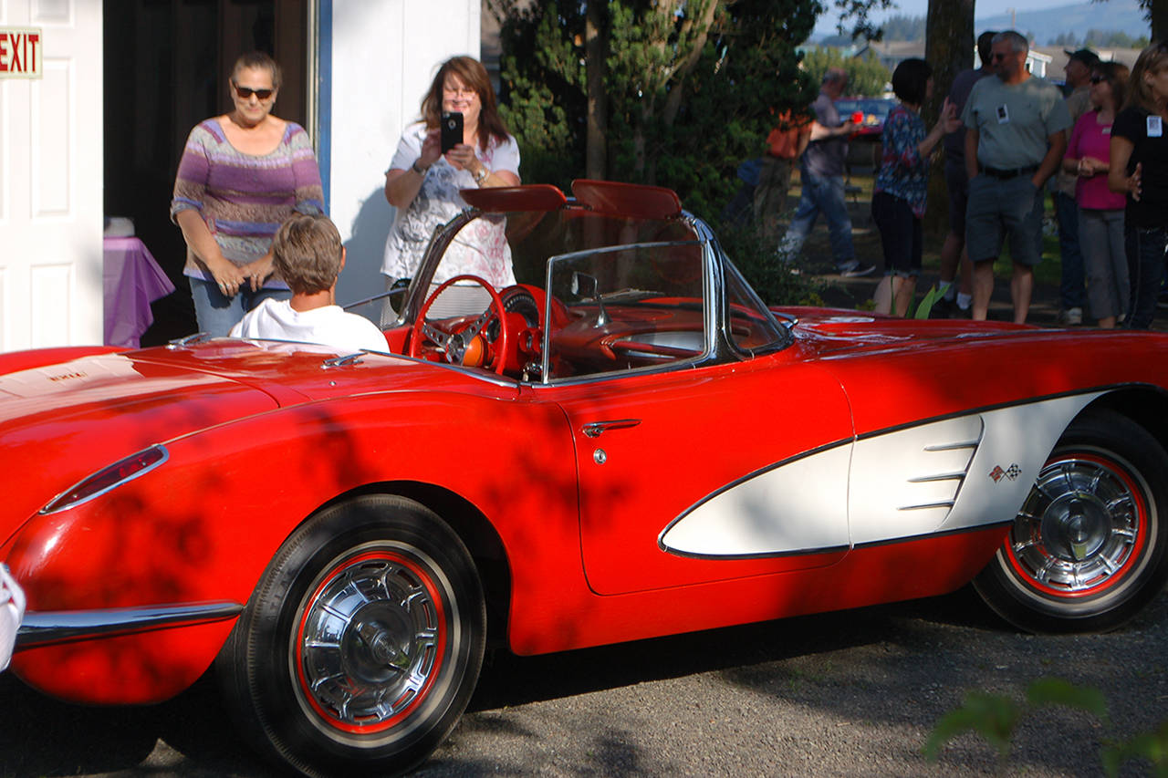 Shelli Robb-Kahler, center, takes a picture of one of her classmates from the Sequim High School class of 1979 sitting in her family’s 1956 Corvette at the 40 year reunion of the class.