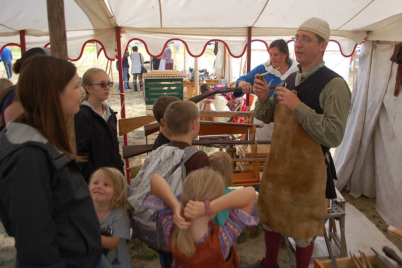 David Rieve, right, discusses Revolutionary War-era gunsmithing with several families in his tent at the Northwest Colonial Festival. Rieve, who is a trained gunsmith and has made numerous muskets and firearms that would be found in that era, has been coming to the Colonial Festival for several years and said that he enjoys the experience. Sequim Gazette photo by Conor Dowley