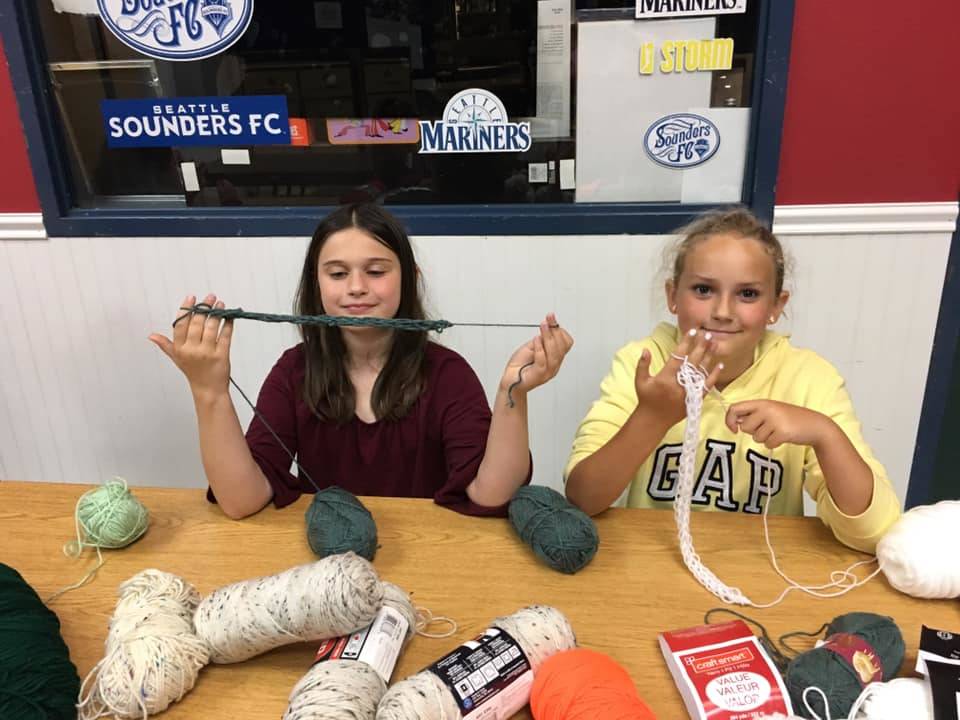 Club members Ryan Adkisson and Keira Headrick work on a finger-knitting project last week. Submitted photo