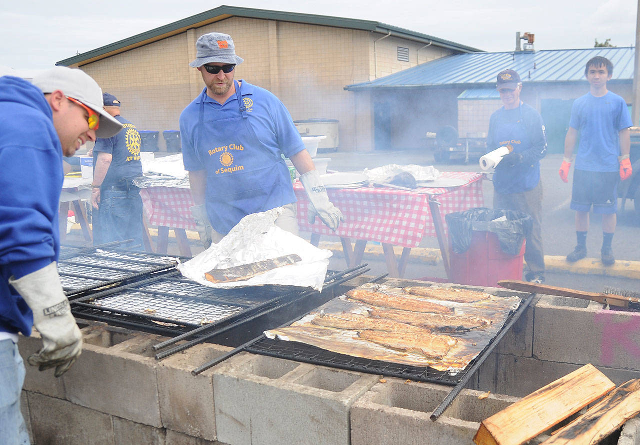 Left, Rotarians look over salmon fillets at the 2019 Rotary Club of Sequim Salmon Bake on Aug. 11. Above, Stuart and Janet McColl take a turn on the “dance floor” as the Dukes of Dabob play at theevent held at the Sequim Boys & Girls Club. Sequim Gazette photos by Michael Dashiell