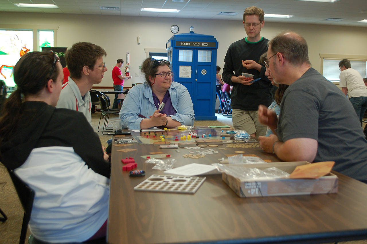Several people from Sequim and Port Angeles work together to learn a new game at Opttacon 2019 at the Guy Cole Event Center on Aug. 17. Sequim Gazette photo by Conor Dowley