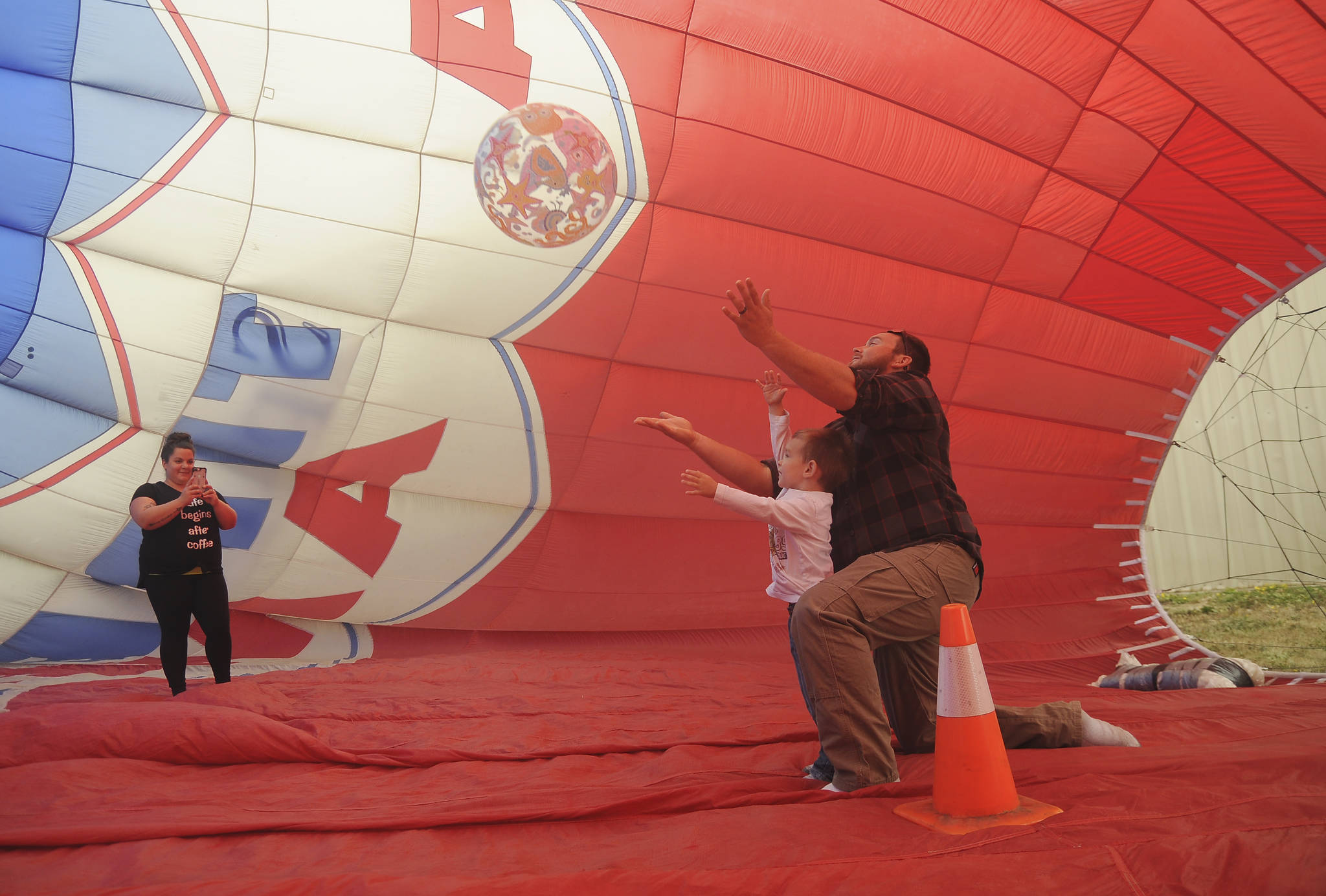 As Amanda Cox takes a photo, and Lukas Cox helps 3-year-old Camden toss an inflated ball in the Morning Star Balloon Co.’s “bouncy balloon” at the 2019 Olympic Peninsula Air Affaire and Sequim Valley Fly-in on Aug. 24. Sequim Gazette photo by Michael Dashiell