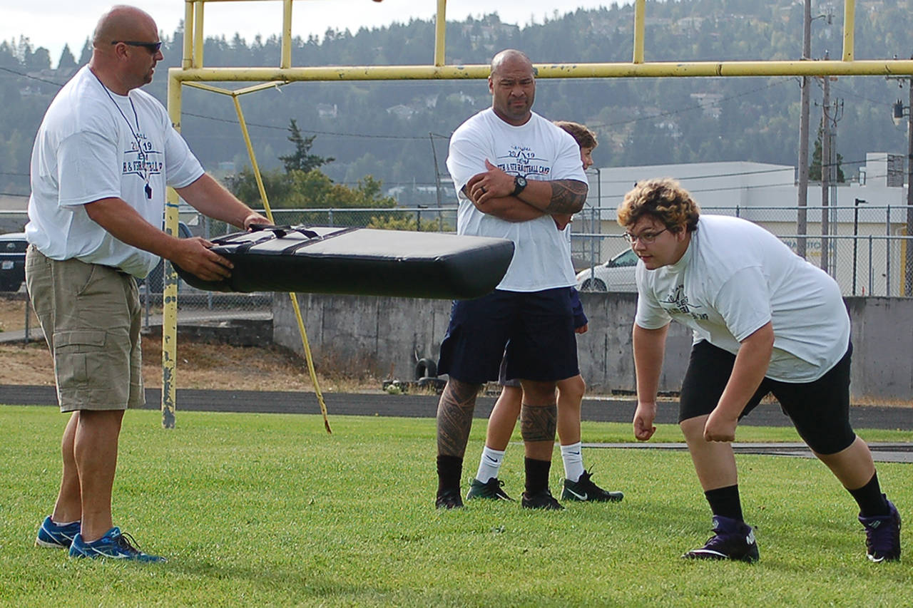 Former Seattle Seahawk offensive lineman Wayne Hunter, center, watches as Sequim Middle School football player Michael Soto, right, runs a defensive line drill at the first annual 7th and 8th grade football camp put on by head coach Sam Salanoa and the SMS football coaching staff on Aug. 24. Sequim Gazette photo by Conor Dowley